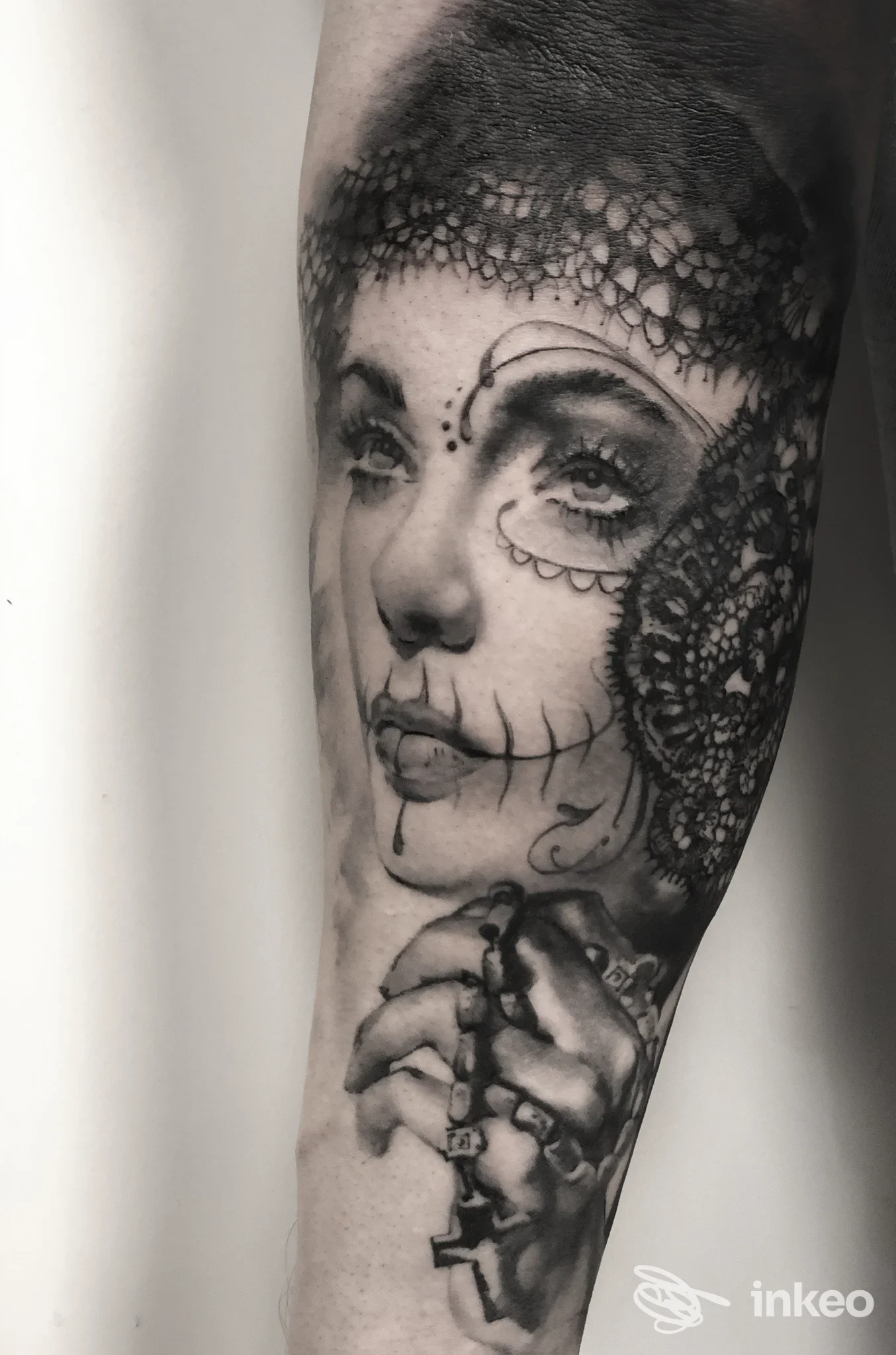 Tatuaggio realistico in bianco e nero su avambraccio raffigurante volto femminile e mano con rosario — DUENDE, Ceccano.