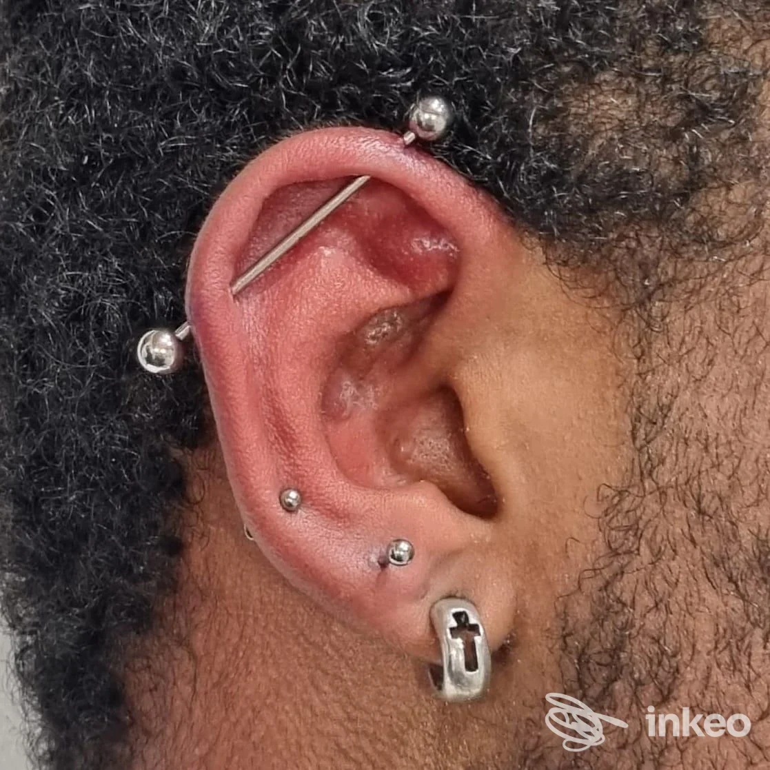Primo piano di un orecchio con più piercing (industrial bar, micropercing e anello al lobo). Sonia Carzaniga Tattoo & Piercing, Burago di Molgora.