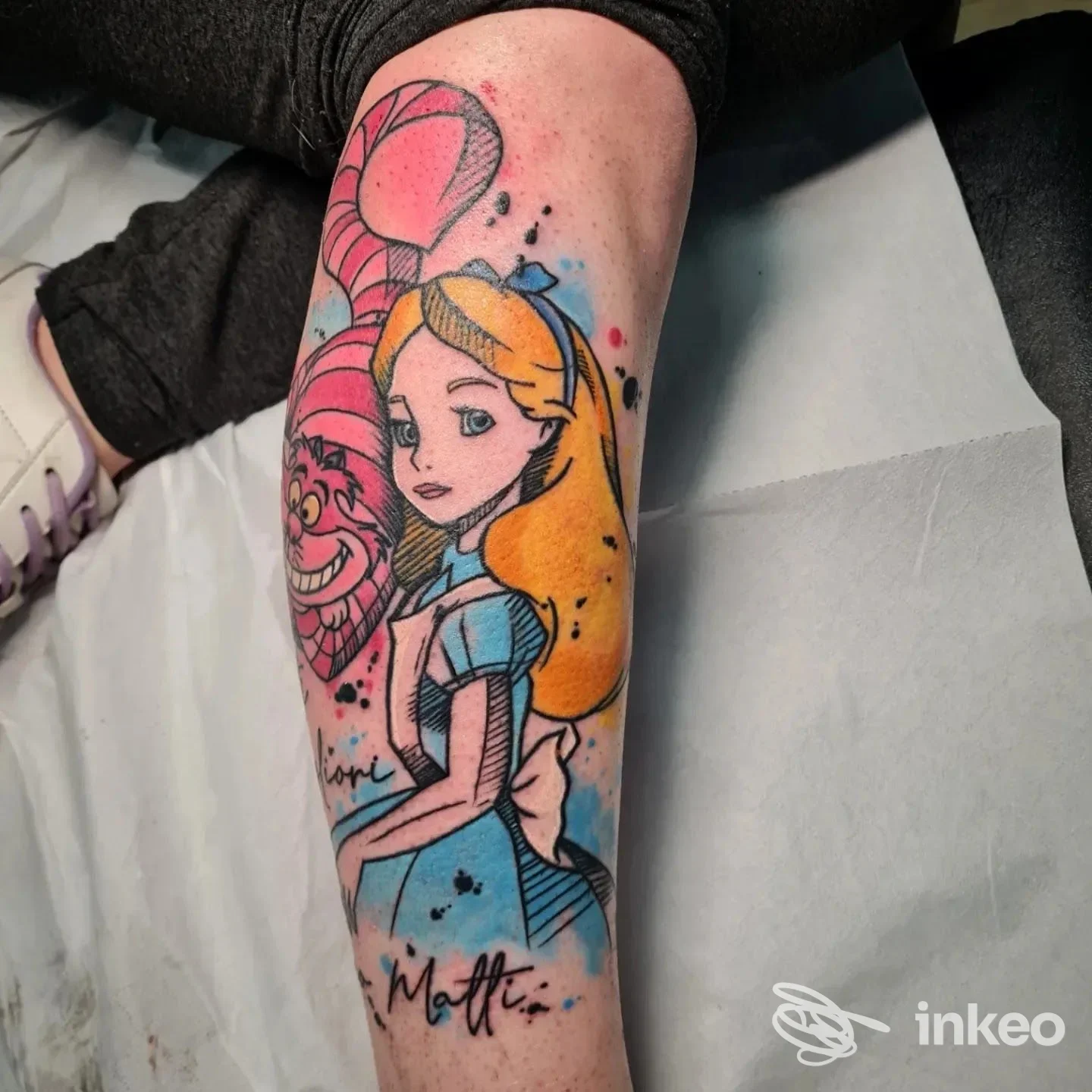Tatuaggio a colori sull'avambraccio con Alice e lo Stregatto, realizzato da Beauty and the Beast tattoo & nails a Lavello.
