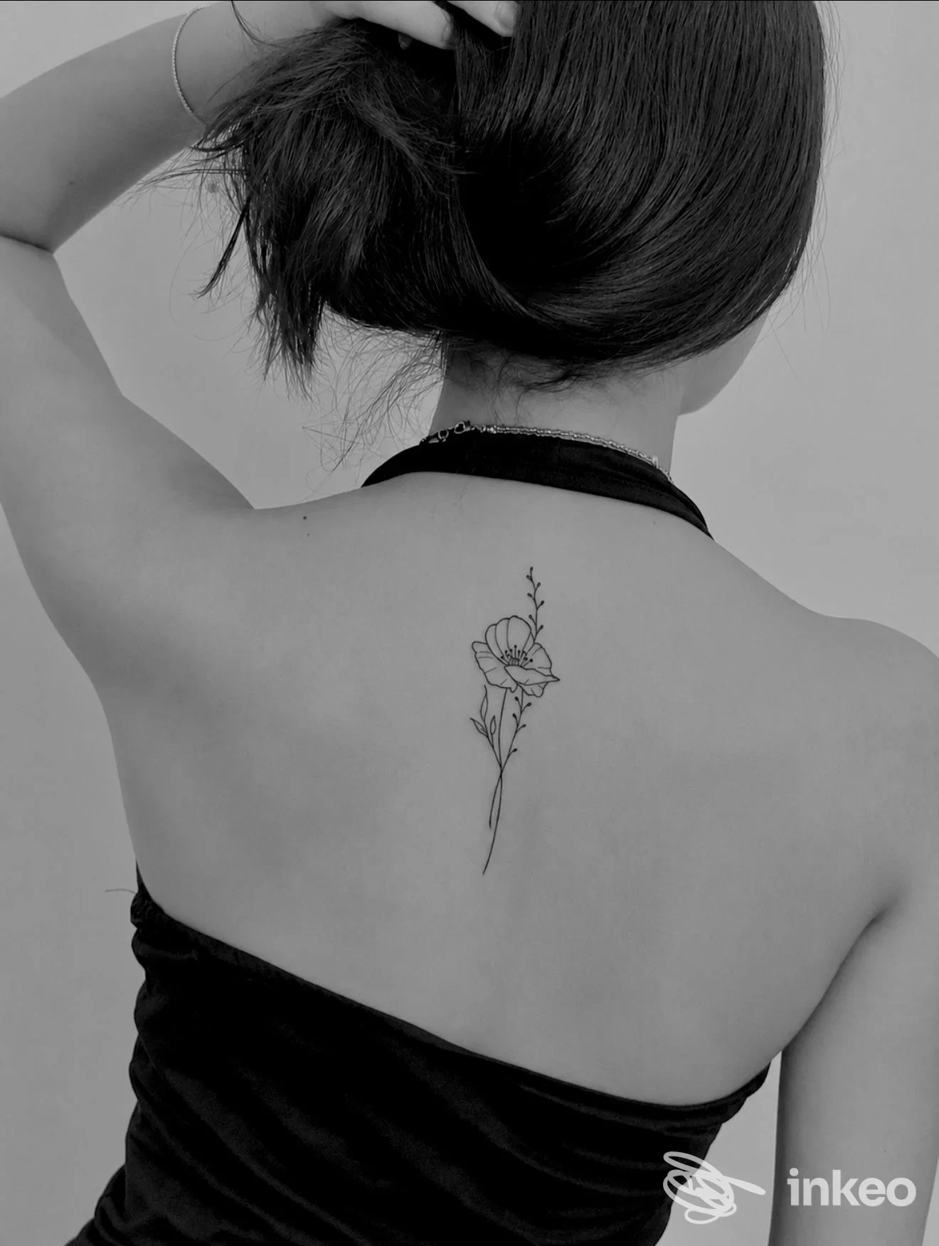 Tatuaggio floreale lineare al centro della parte alta della schiena, foto scattata nello studio Sartoria dell’Inchiostro a Verona.