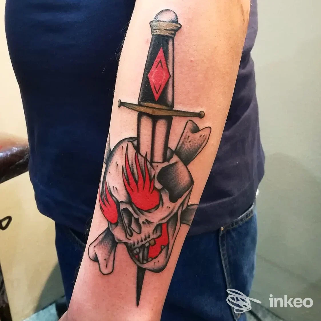 Tatuaggio su avambraccio con teschio, fiamme rosse e daga – Old bones, Cogoleto.