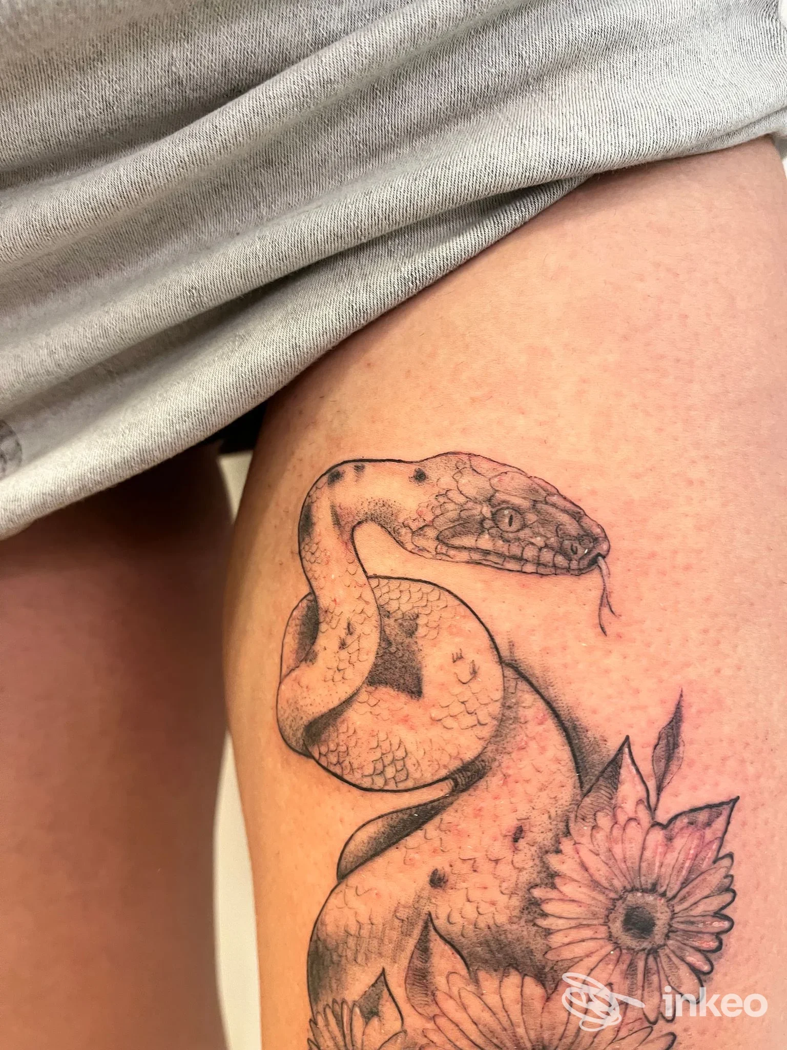 Tatuaggio su coscia con serpente e margherita, realizzato da nanArt a Vieste.