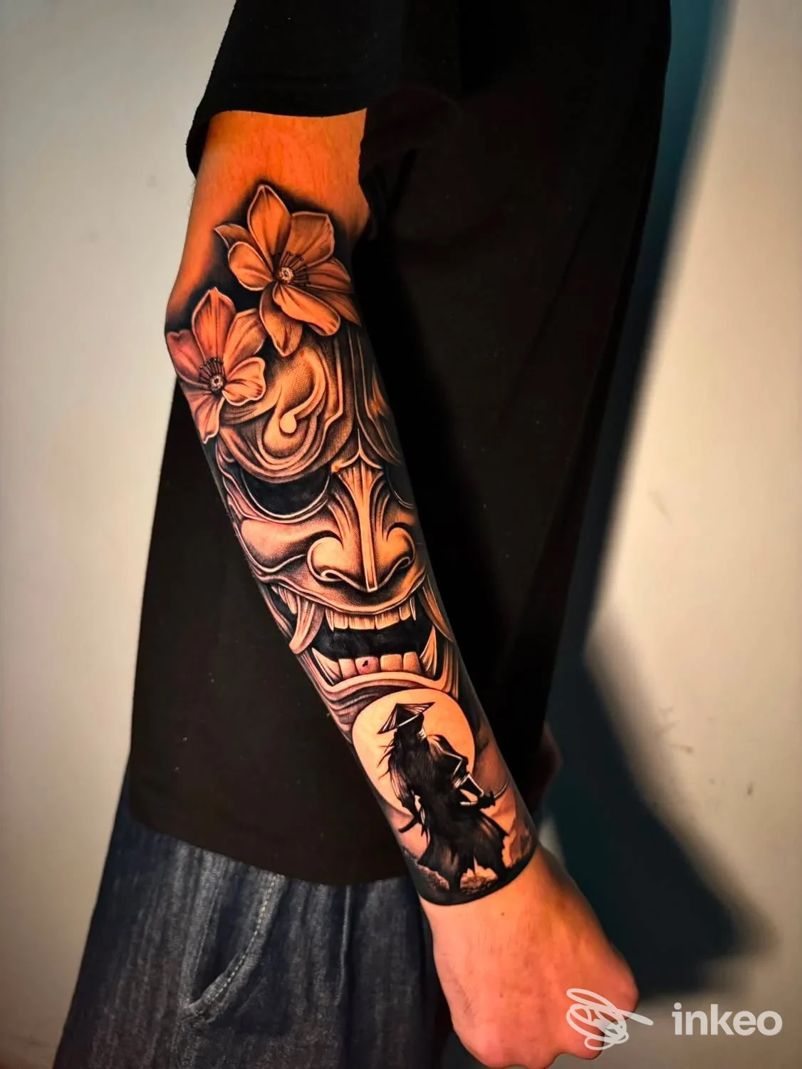 Avambraccio tatuato con maschera stilizzata e fiori, foto caricato da Atramento Studio, Alessandria.