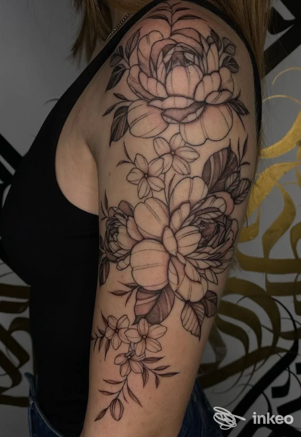 Porzione di braccio sinistro con un grande tatuaggio floreale in stile linework, fiori grandi e piccoli, delineazioni nere sulla pelle, realizzato presso CELLAR DOOR Tattoo Studio.