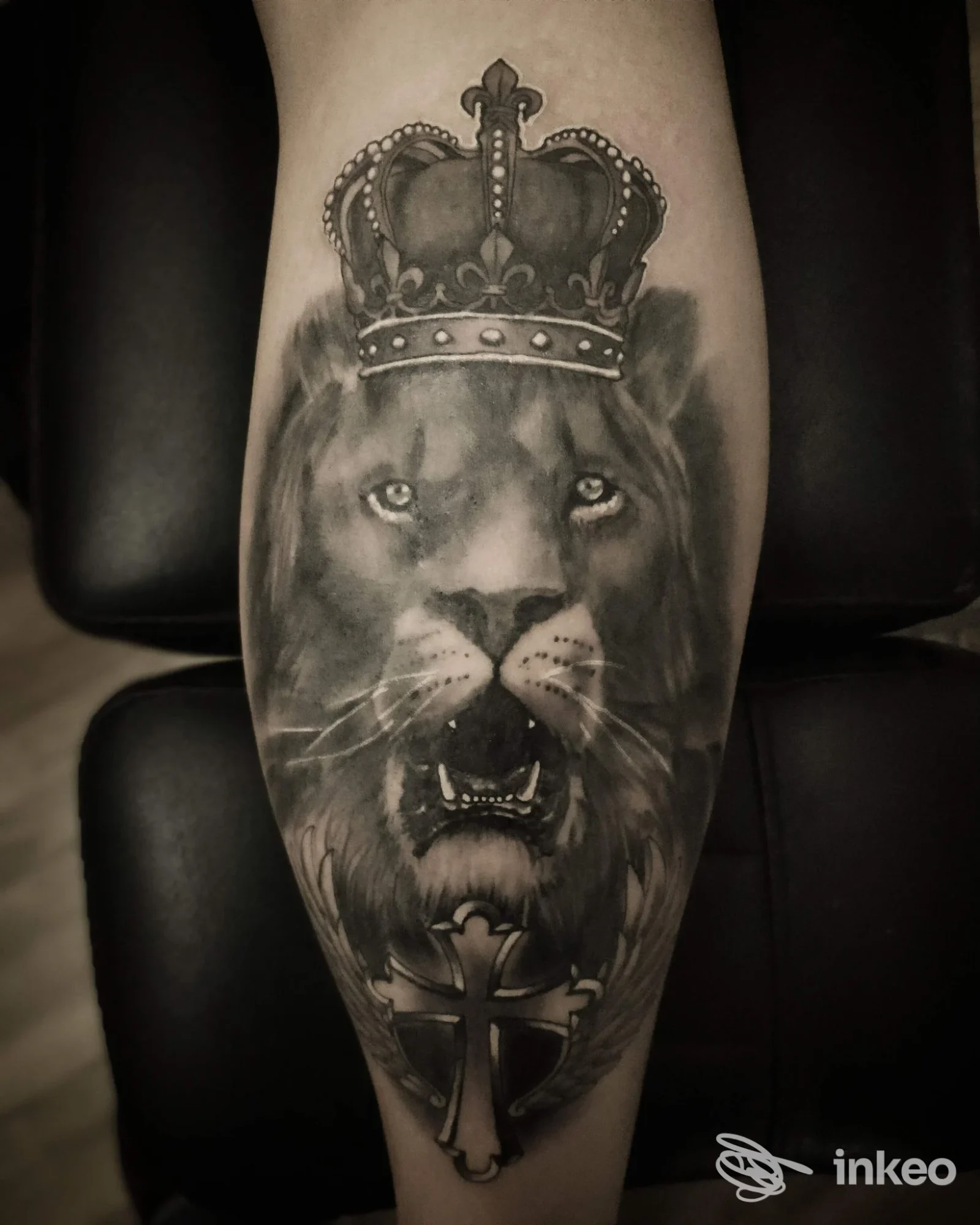 Tatuaggio black & grey di un leone coronato con croce, fotografato sul polpaccio. Box Tat2 Studio, Palermo.