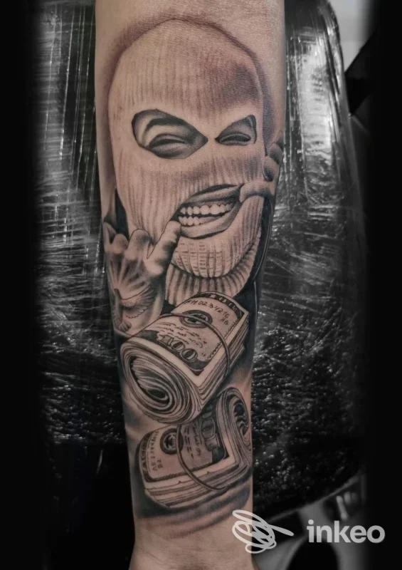 Primo piano di un tatuaggio realistico sull'avambraccio raffigurante una figura con passamontagna e rotoli di banconote; foto dello studio Black Star, Venezia.