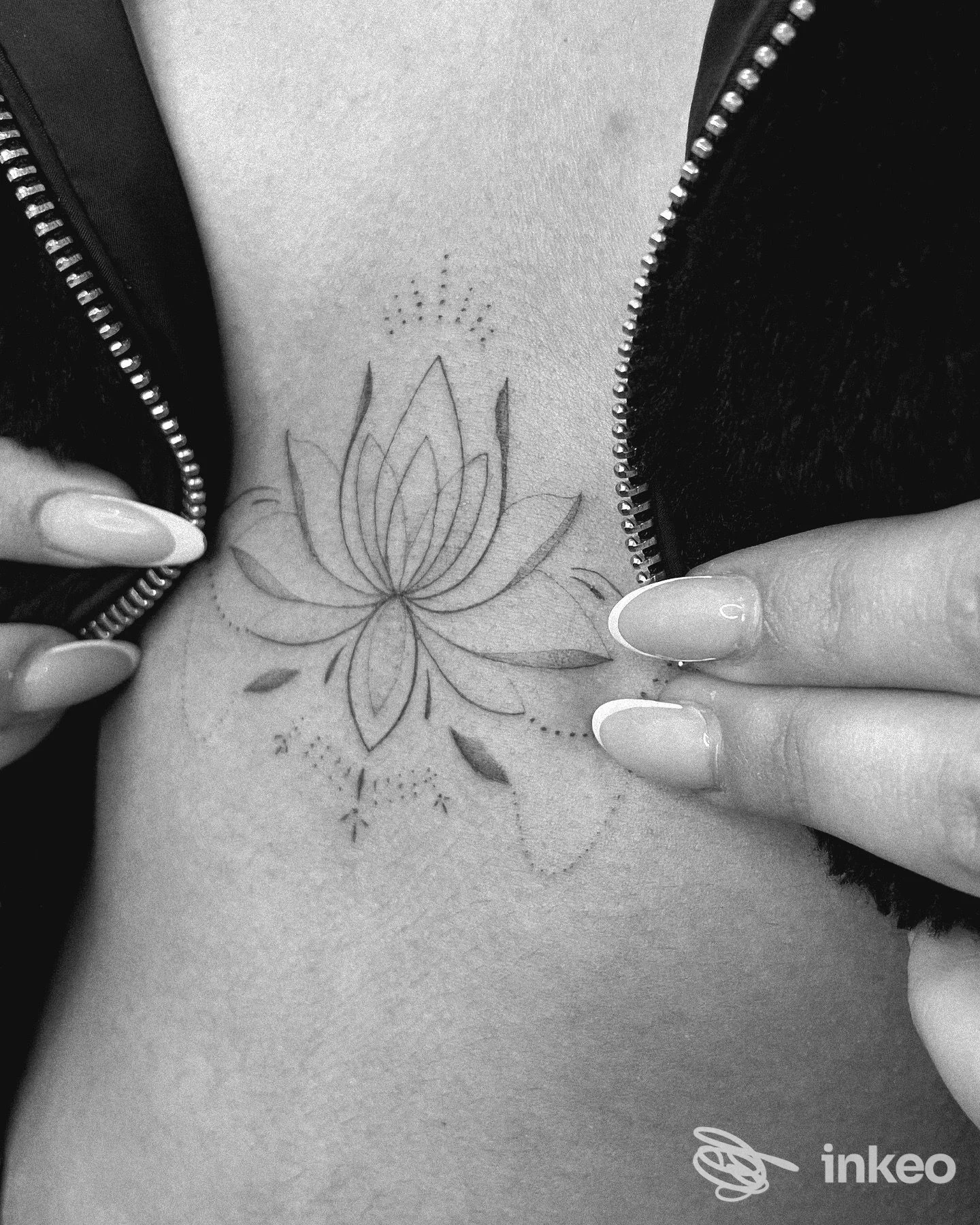 Tatuaggio a loto sul torace centrale; mani aprono la giacca. AMBER TATTOO E PIERCING, Ciampino.