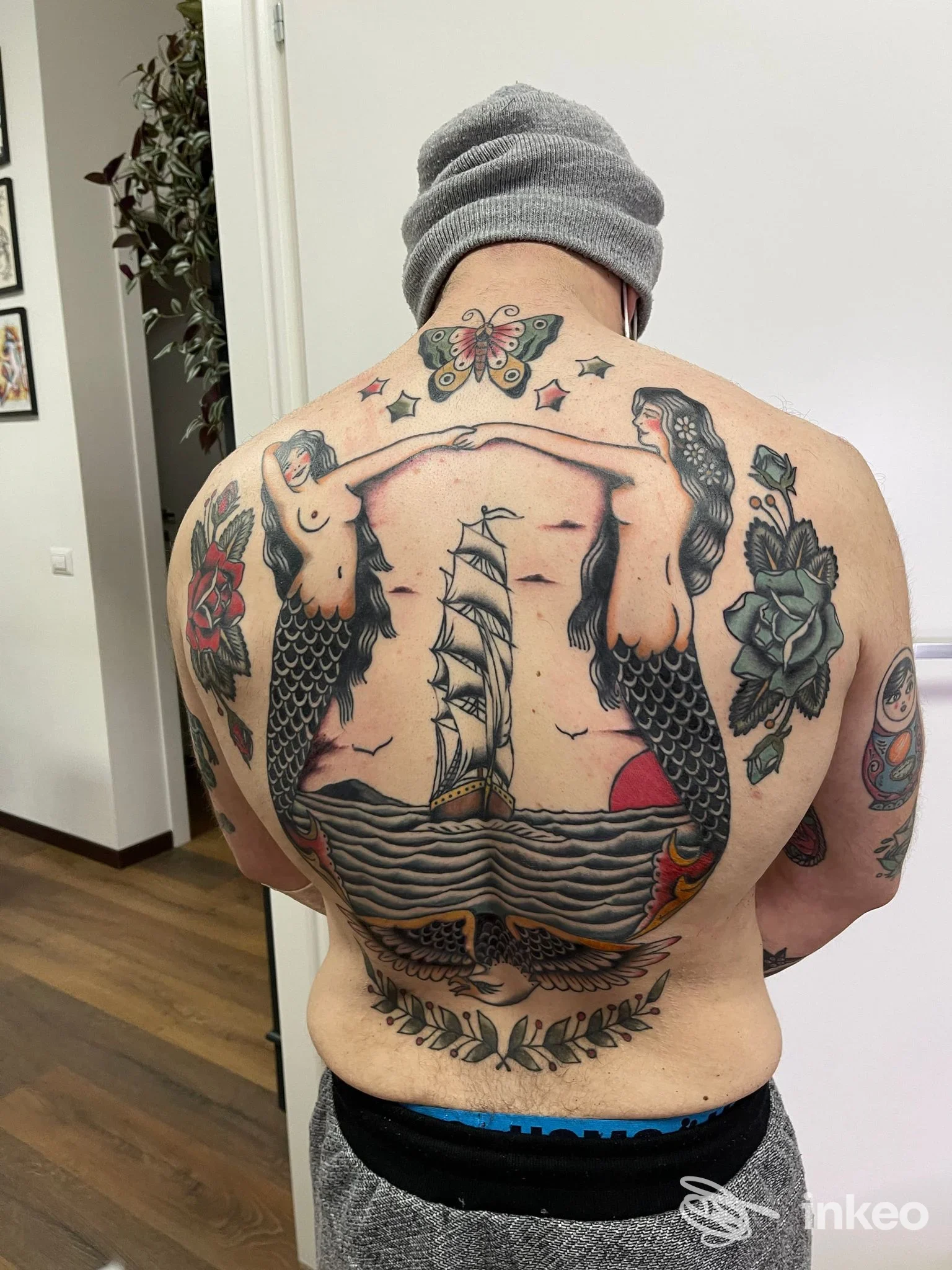 Grande tatuaggio sulla schiena con sirene e nave, fotografato presso Calipso Tattoo Studio a Viterbo.