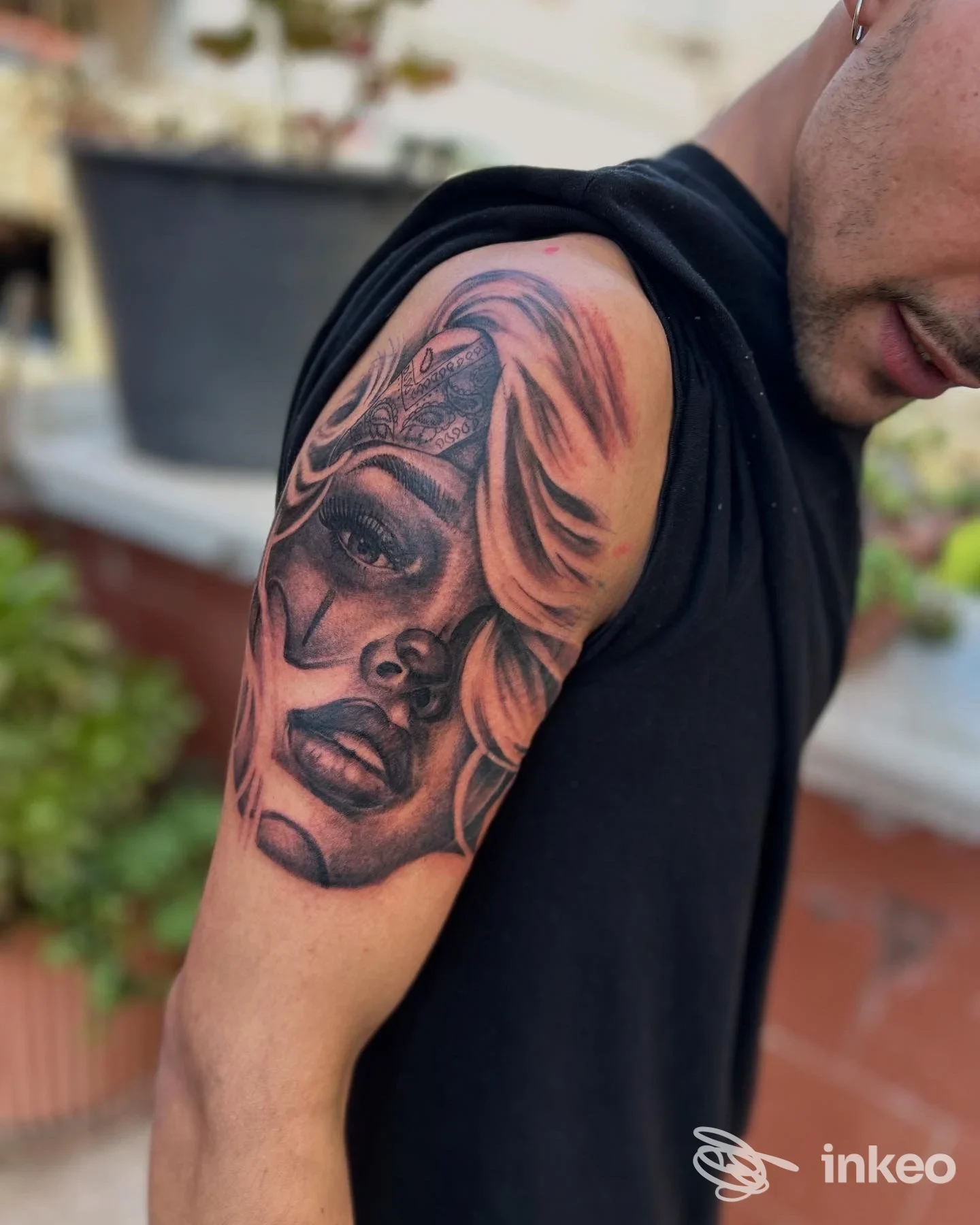 Tatuaggio realistico su braccio superiore raffigurante un volto femminile, foto scattata in esterno. LEON TATTOO STUDIO, Bari.