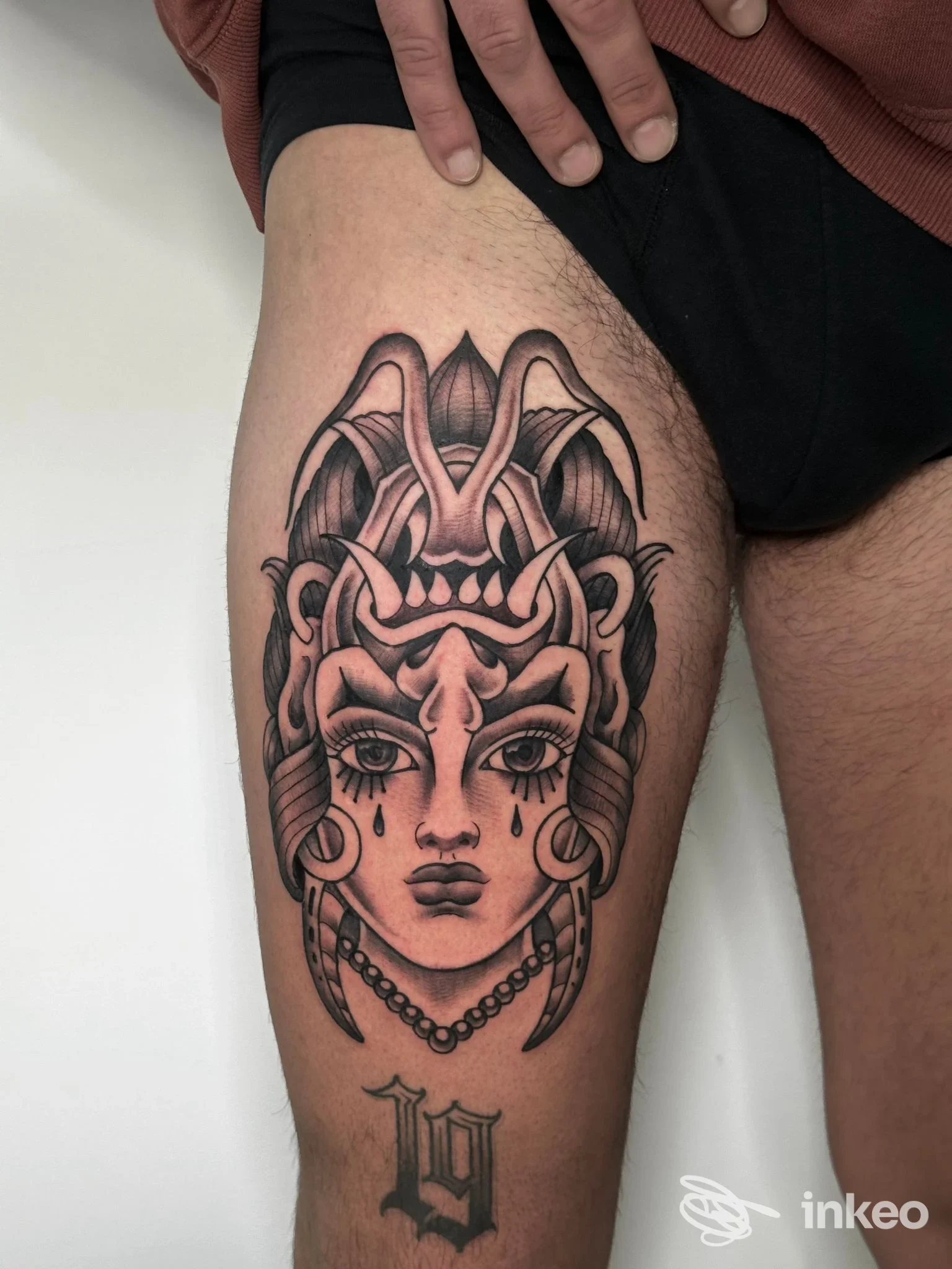 Tatuaggio su coscia che ritrae un volto femminile stilizzato con ornamenti e perline, realizzato da Outline Bari a Bari.