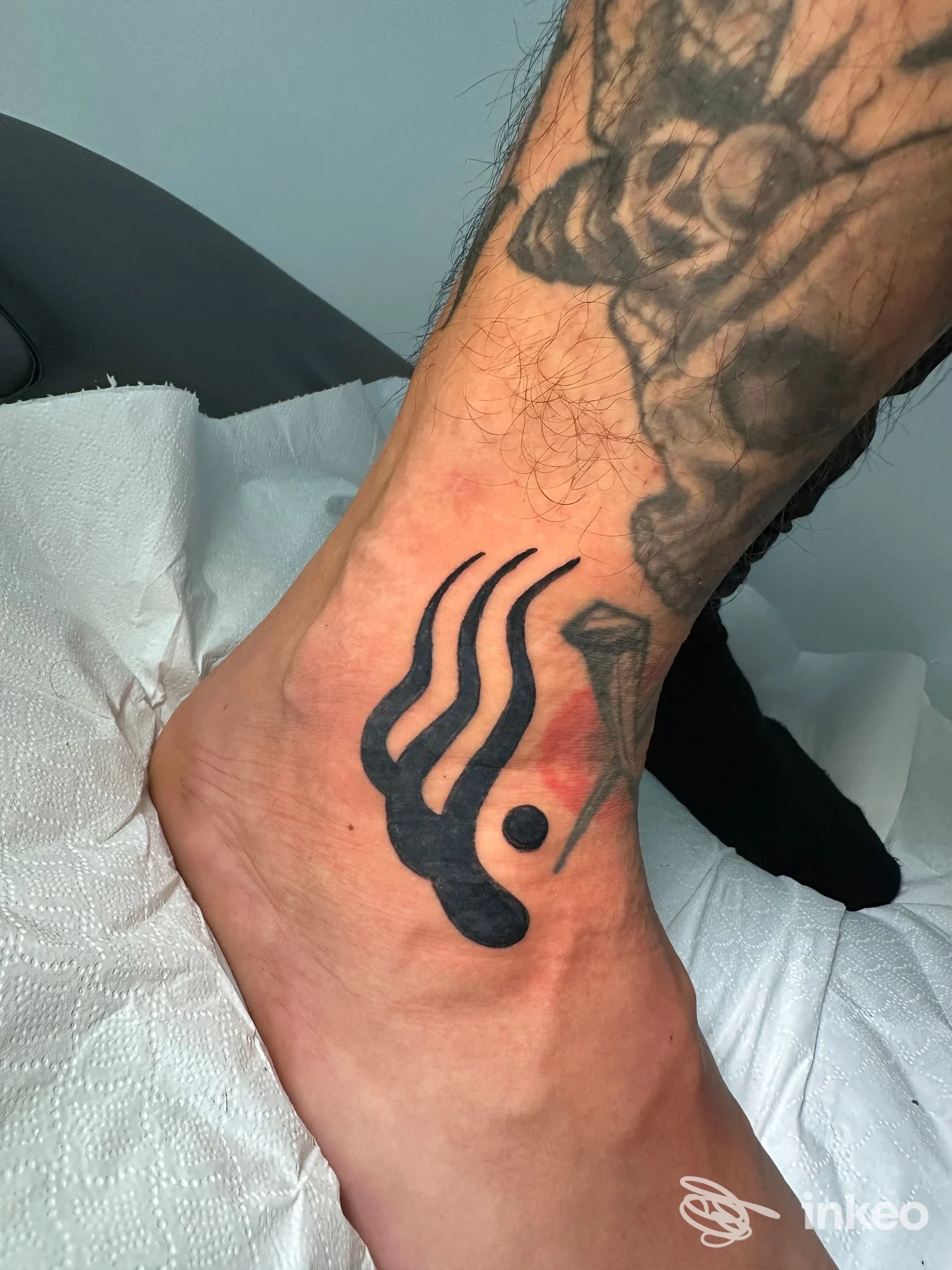 Dettaglio di tatuaggio nero sulla caviglia, pelle leggermente arrossata; Outline Bari, Bari.