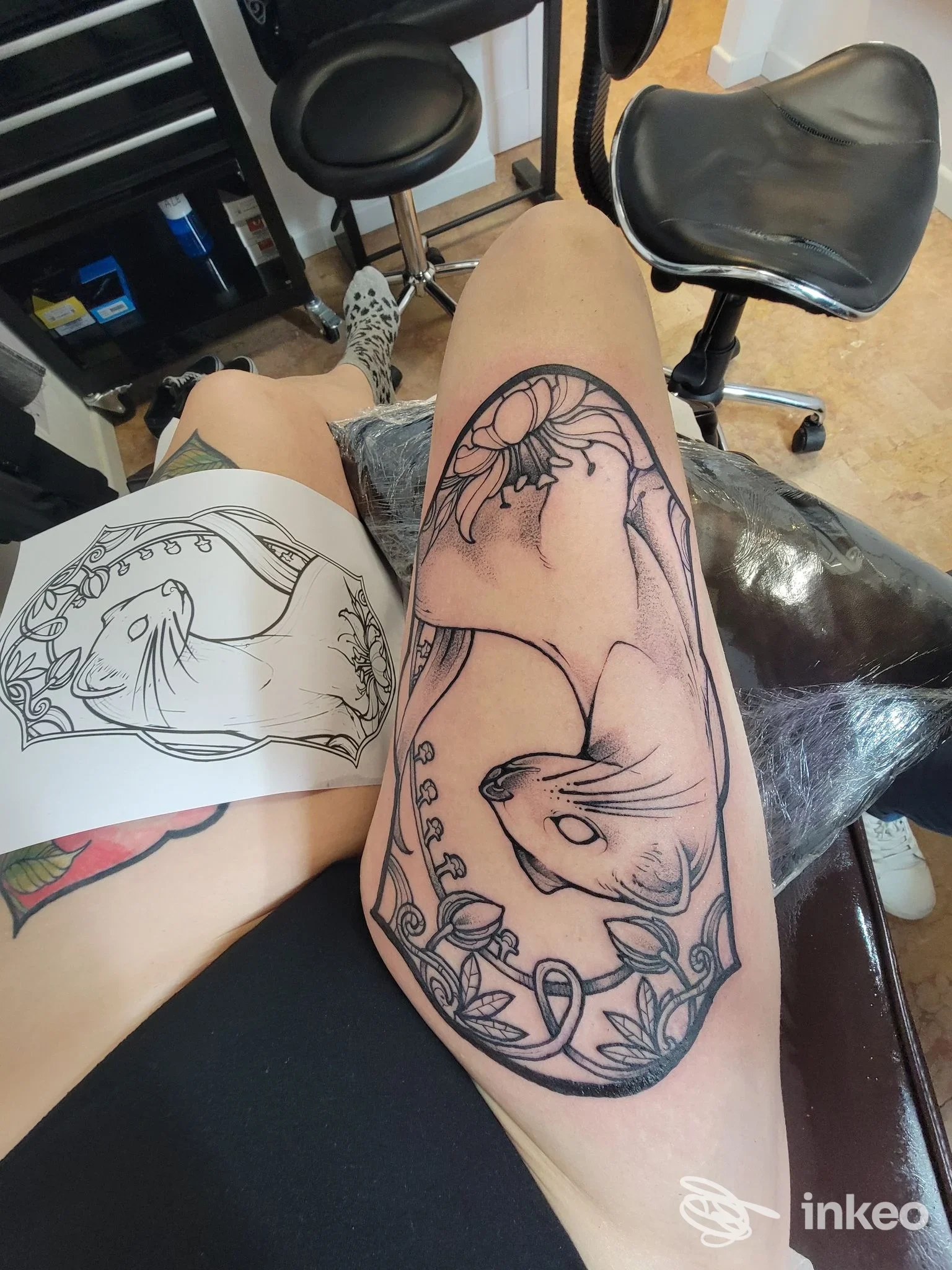 Tatuaggio nero su coscia con due pesci e motivi floreali, foto scattata nello studio Black Water Tattoo Parlour a Verona.