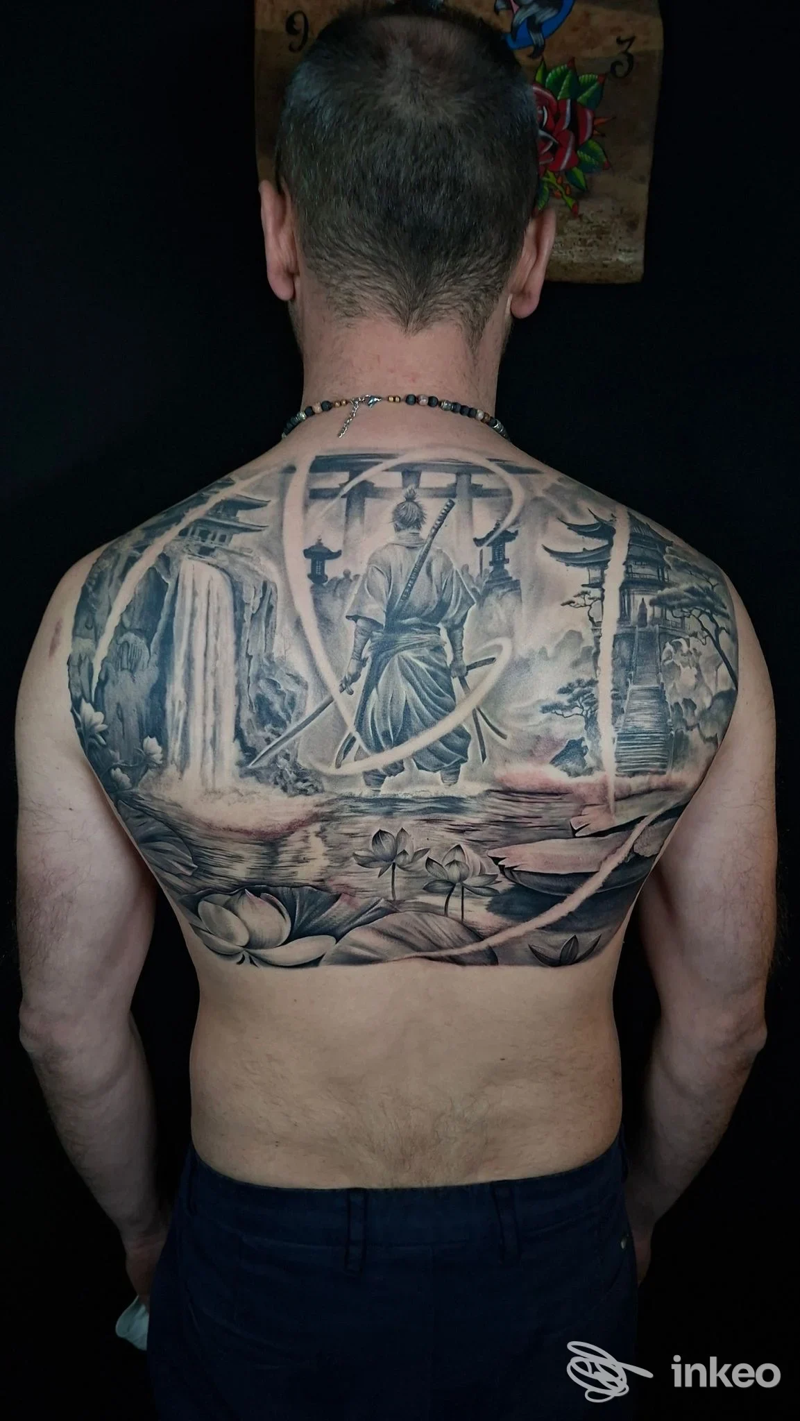 Grande tatuaggio a schiena intera in bianco e nero, scena figurativa con figura centrale, cascate e motivi floreali — Giulio Crolla Tattoo Studio, Santi Cosma e Damiano