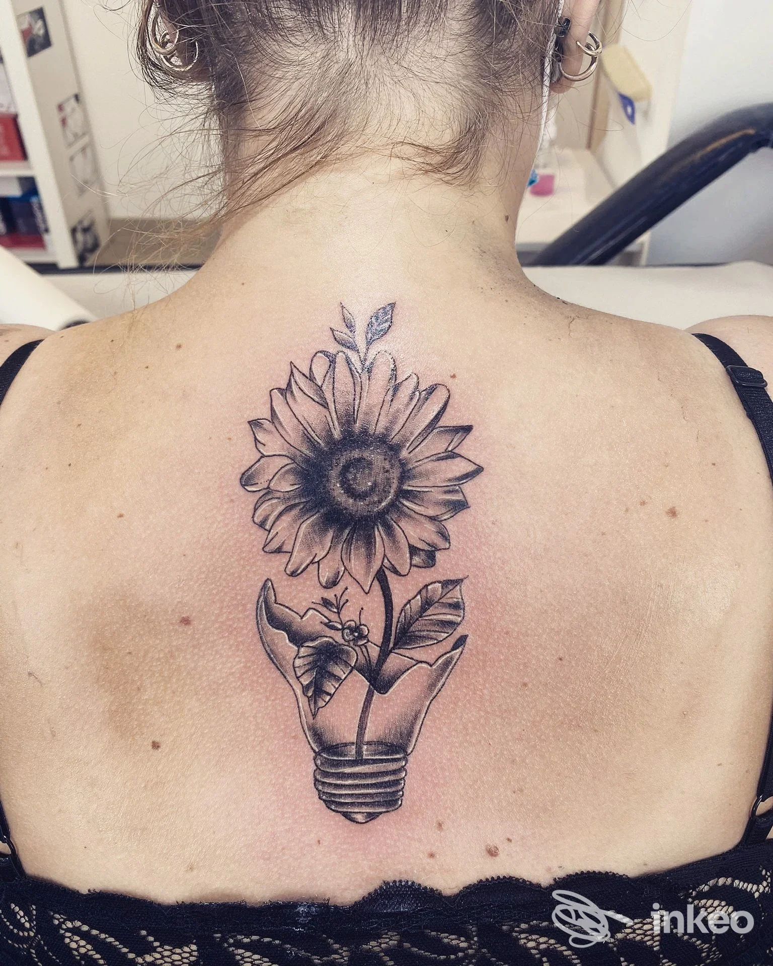 Tatuaggio in bianco e nero sul dorso: girasole che nasce da una lampadina, foto condivisa dallo studio Rock 'n' Roll Tattoo Verona a Peschiera del Garda.