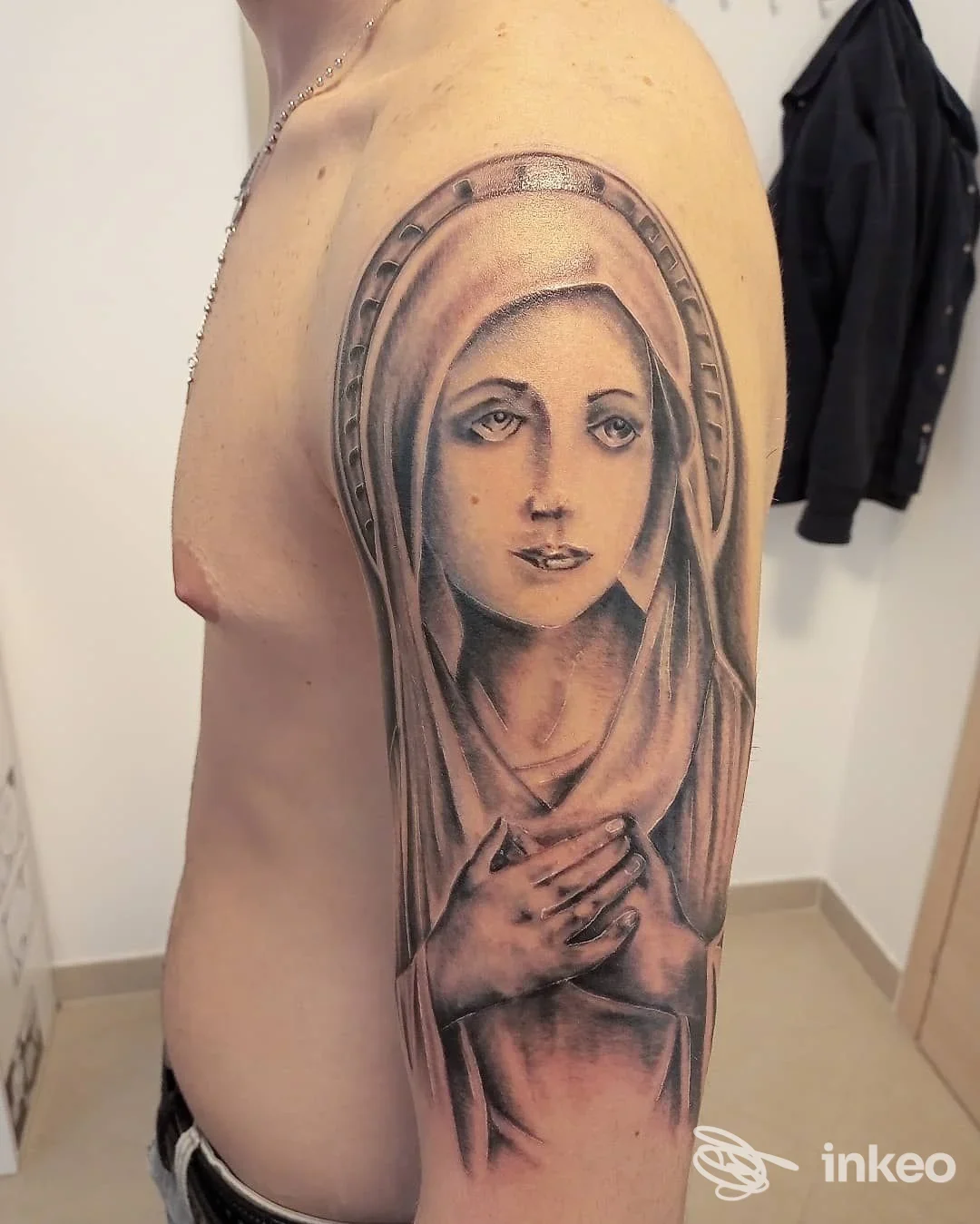 Grande tatuaggio in bianco e nero di volto velato sul deltoide, foto fornita da Rock 'n' Roll Tattoo Verona a Peschiera del Garda.