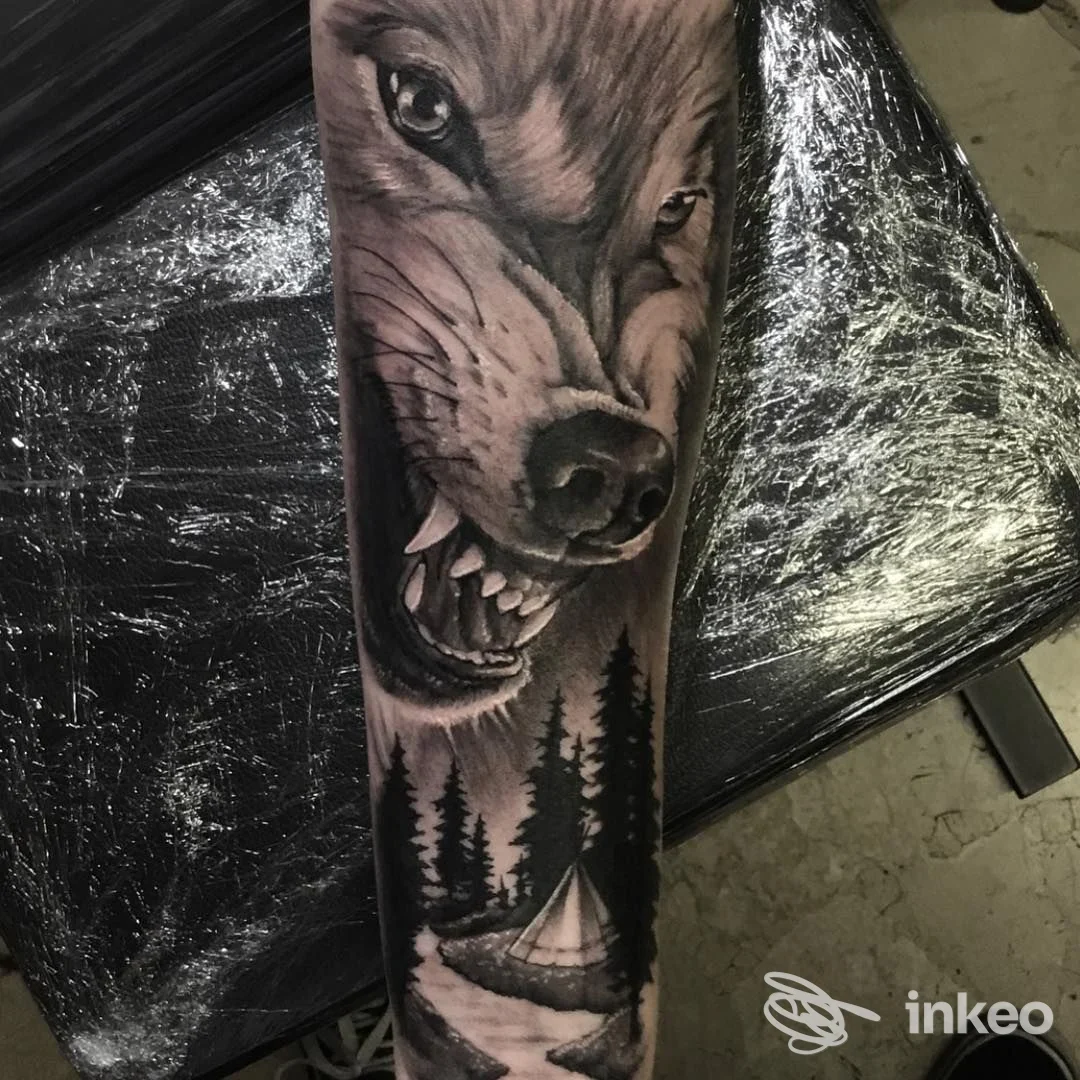 Tatuaggio realistico in bianco e nero di un lupo e campeggio sull'avambraccio, Aseptic Studio, Trento.