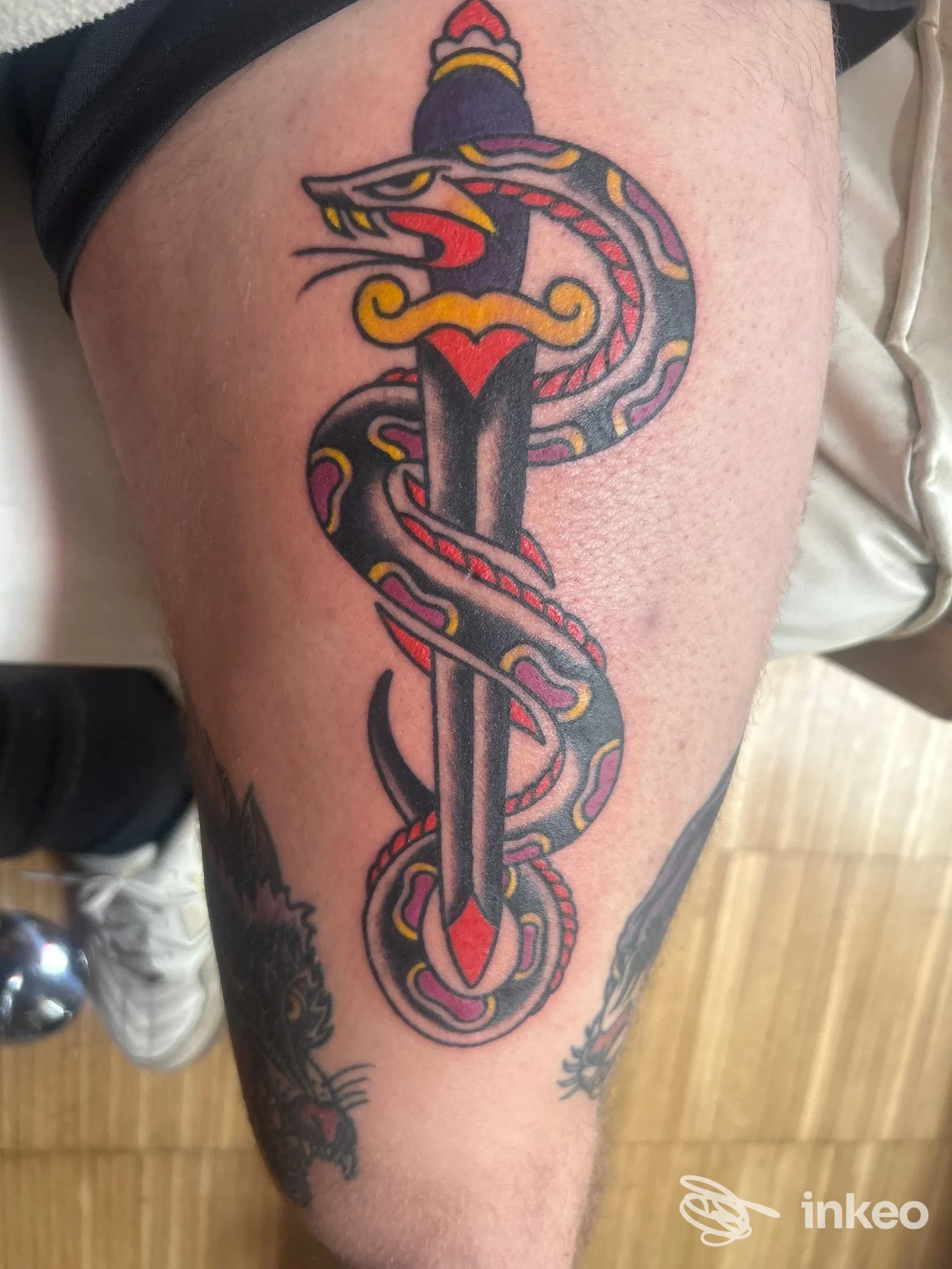 Tatuaggio tradizionale su polpaccio: pugnale verticale avvolto da serpente nero, rosso e giallo. Electric Tiger House, Vicenza.