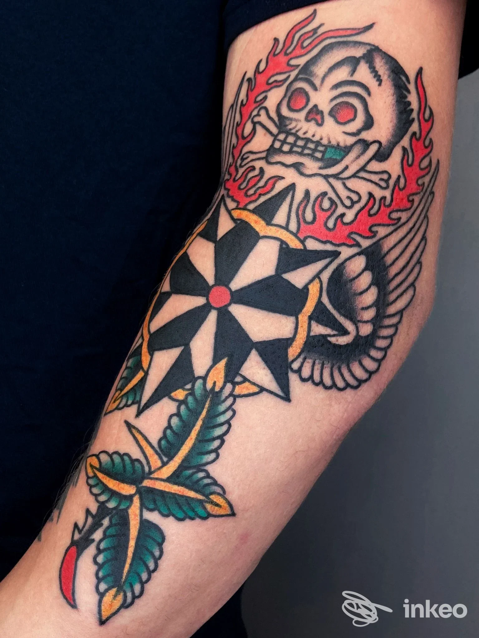 Tatuaggio tradizionale su avambraccio: teschio fiammeggiante e fiore stilizzato. Electric Tiger House, Vicenza.