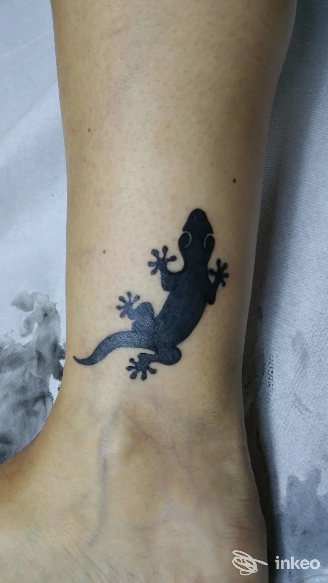Piccolo tatuaggio di geco nero alla caviglia, realizzato da Tora Tattoo a Rio Saliceto.