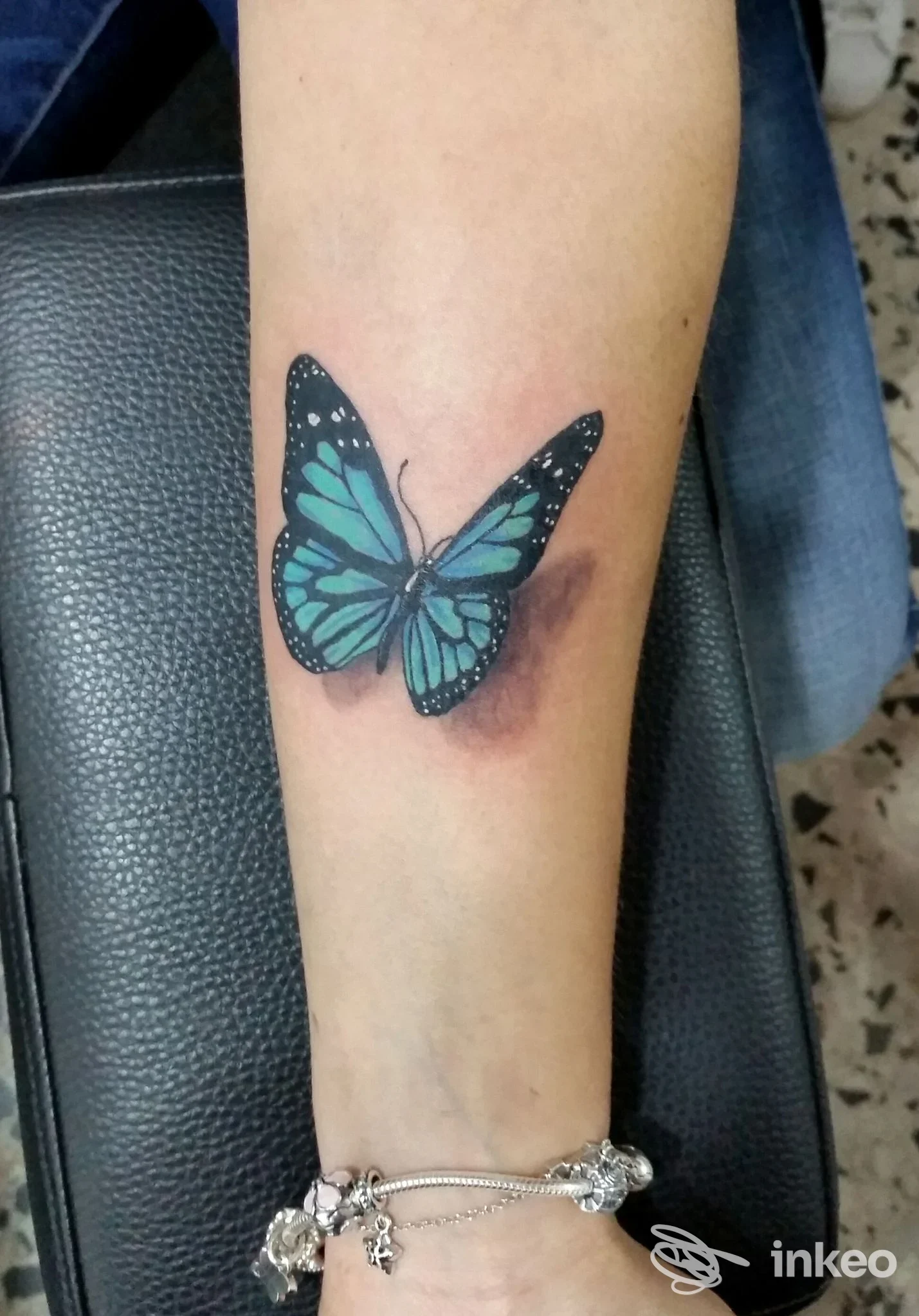 Tatuaggio a forma di farfalla blu/verde sull'avambraccio, fotografato allo Studio Tattoo Studio Jordan Mammola a Civitavecchia.