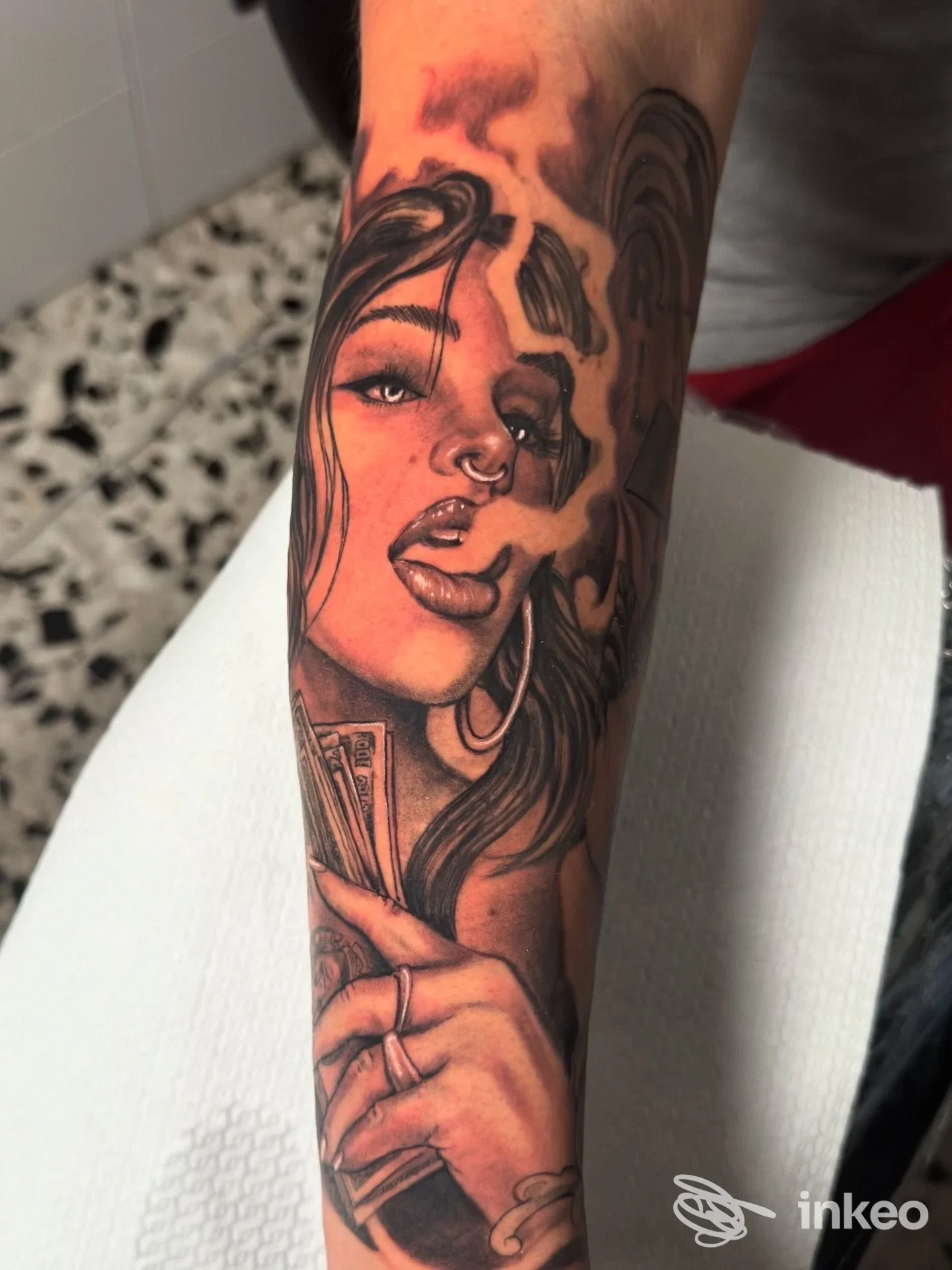 Tatuaggio realistico sul davanti avambraccio con volto femminile e mano che tiene banconote, Tattoo Studio Jordan Mammola, Civitavecchia.