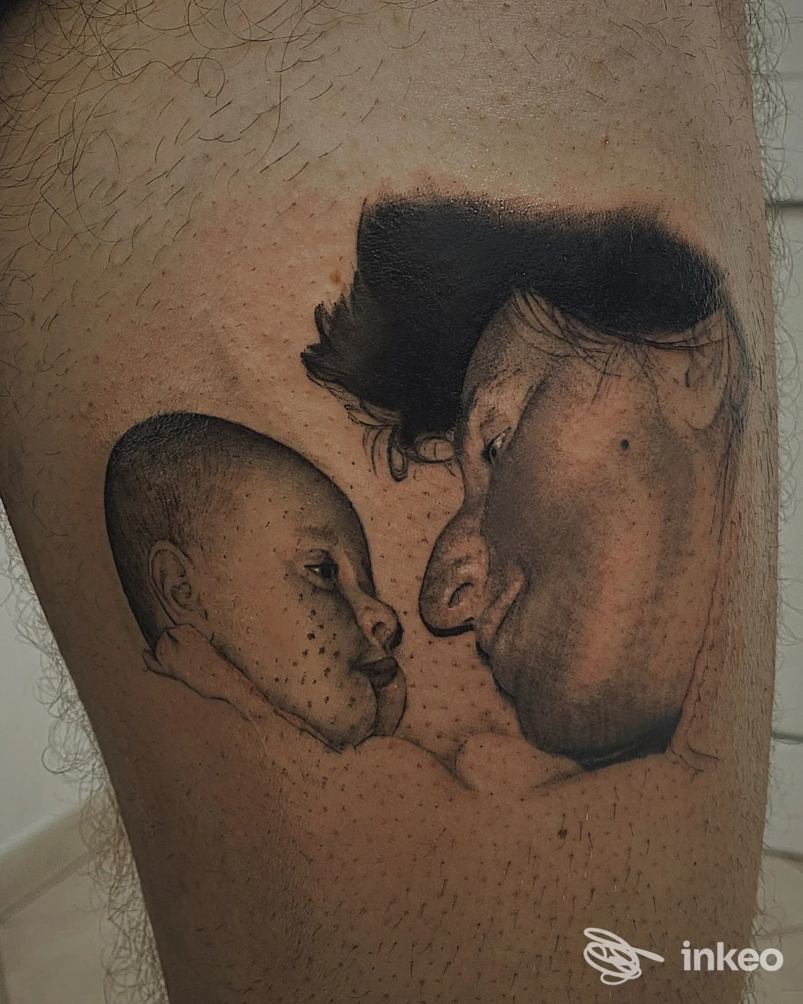 Tatuaggio realistico di due volti in nero e grigio sulla coscia, fotografia inviata da Inked House Studio, Savona.