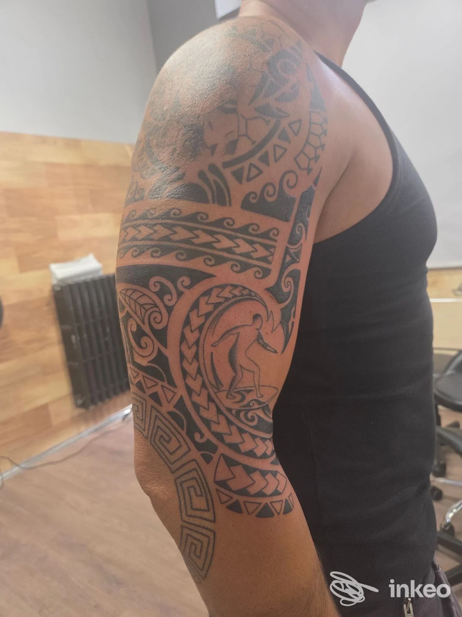 Manica tribale nera su braccio e spalla maschili, fotografata nello studio; lavoro di Indaco Tattoo crew a Torino, vista laterale dettagliata.
