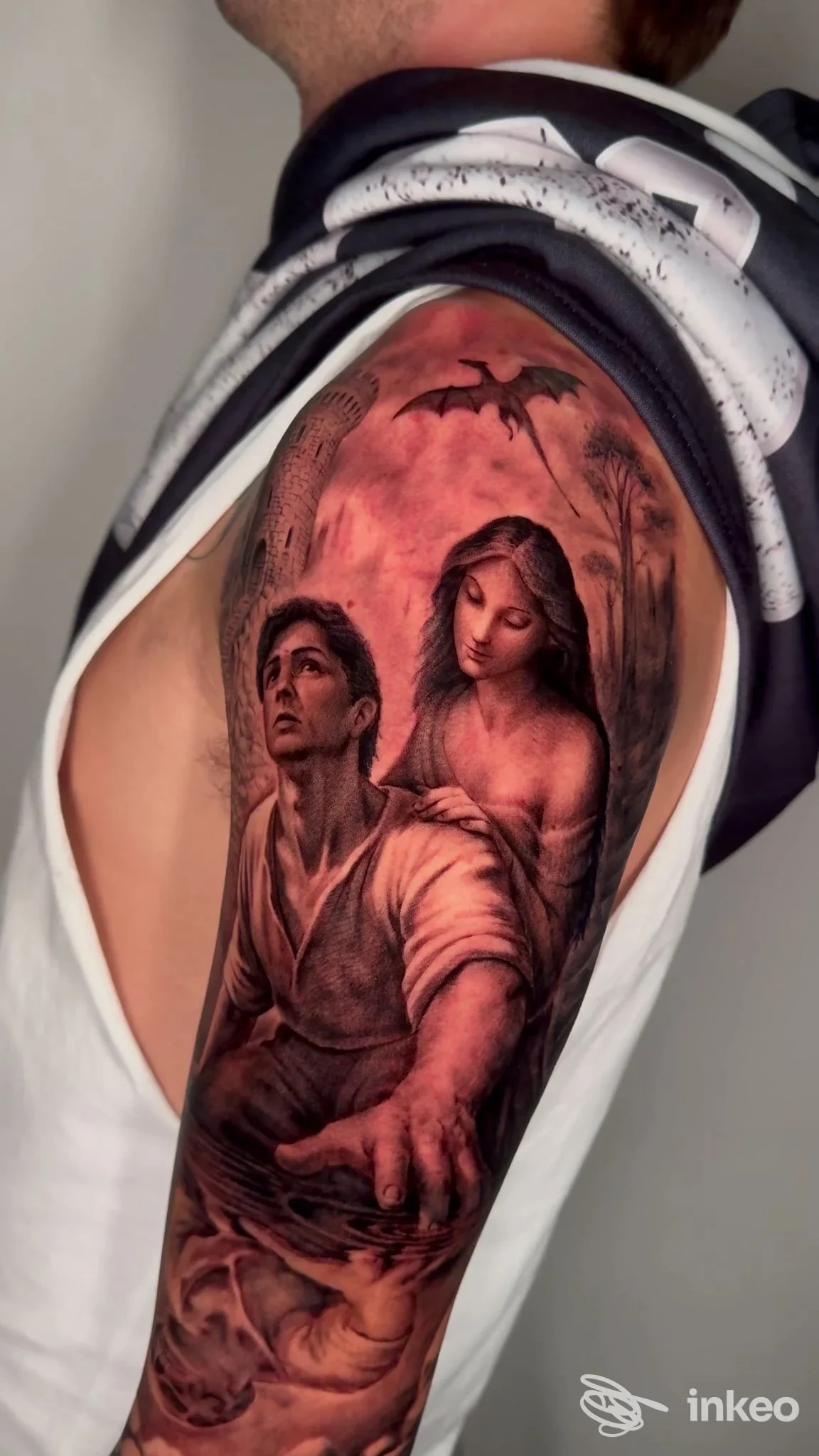 Grande tatuaggio figurativo su braccio superiore, fotografato da Kappacento tattoo art studio a Molfetta, con figure realistiche e toni caldi.