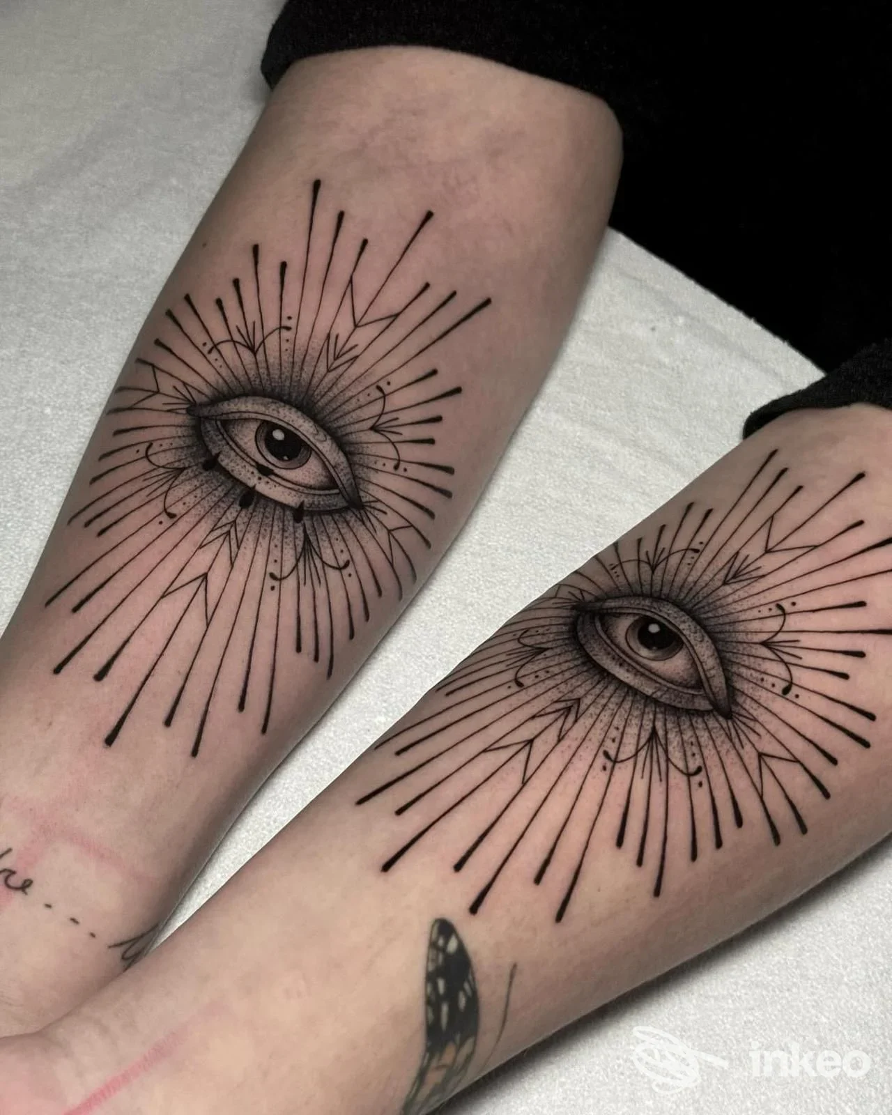 Due tatuaggi identici a forma di occhio stilizzato con raggi sul lato interno degli avambracci, realizzati da Indelebile Studio Tattoo - Tatuaggi Sava, Sava.