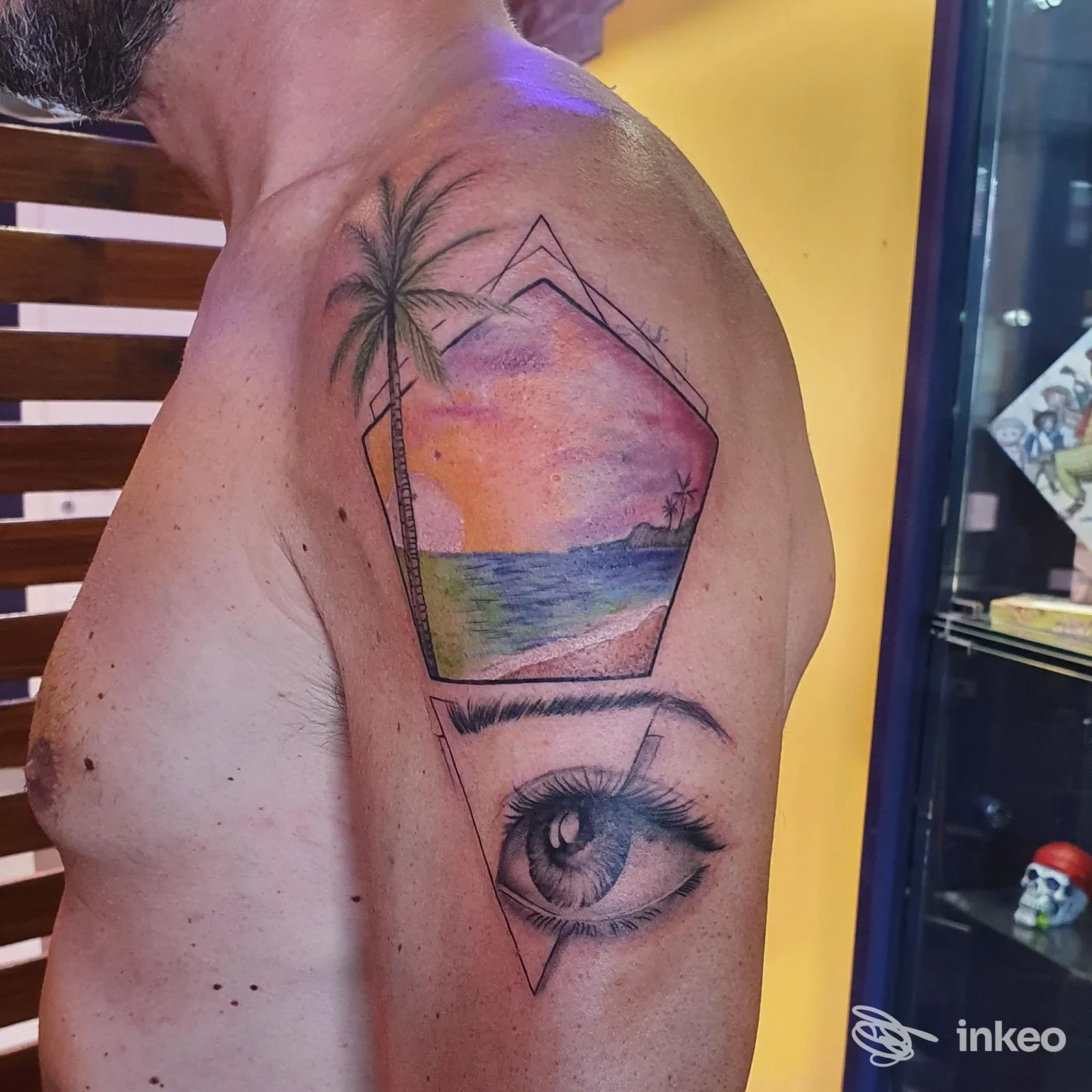 Tatuaggio su spalla con paesaggio marino al tramonto e un grande occhio in bianco e nero, foto fornita da Vele Nere ink heArt, Osimo.