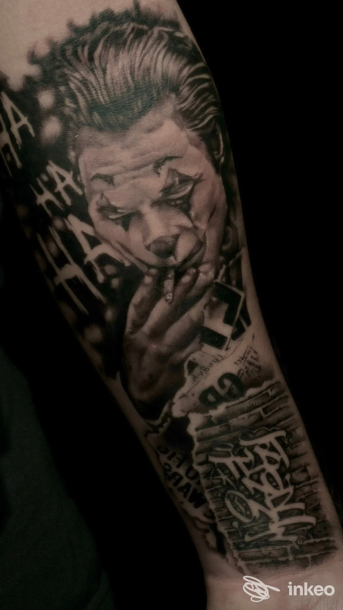 Tatuaggio realistico in bianco e nero su avambraccio raffigurante il volto di un Joker, immagine fornita da Twenty Ink Studio Barletta.