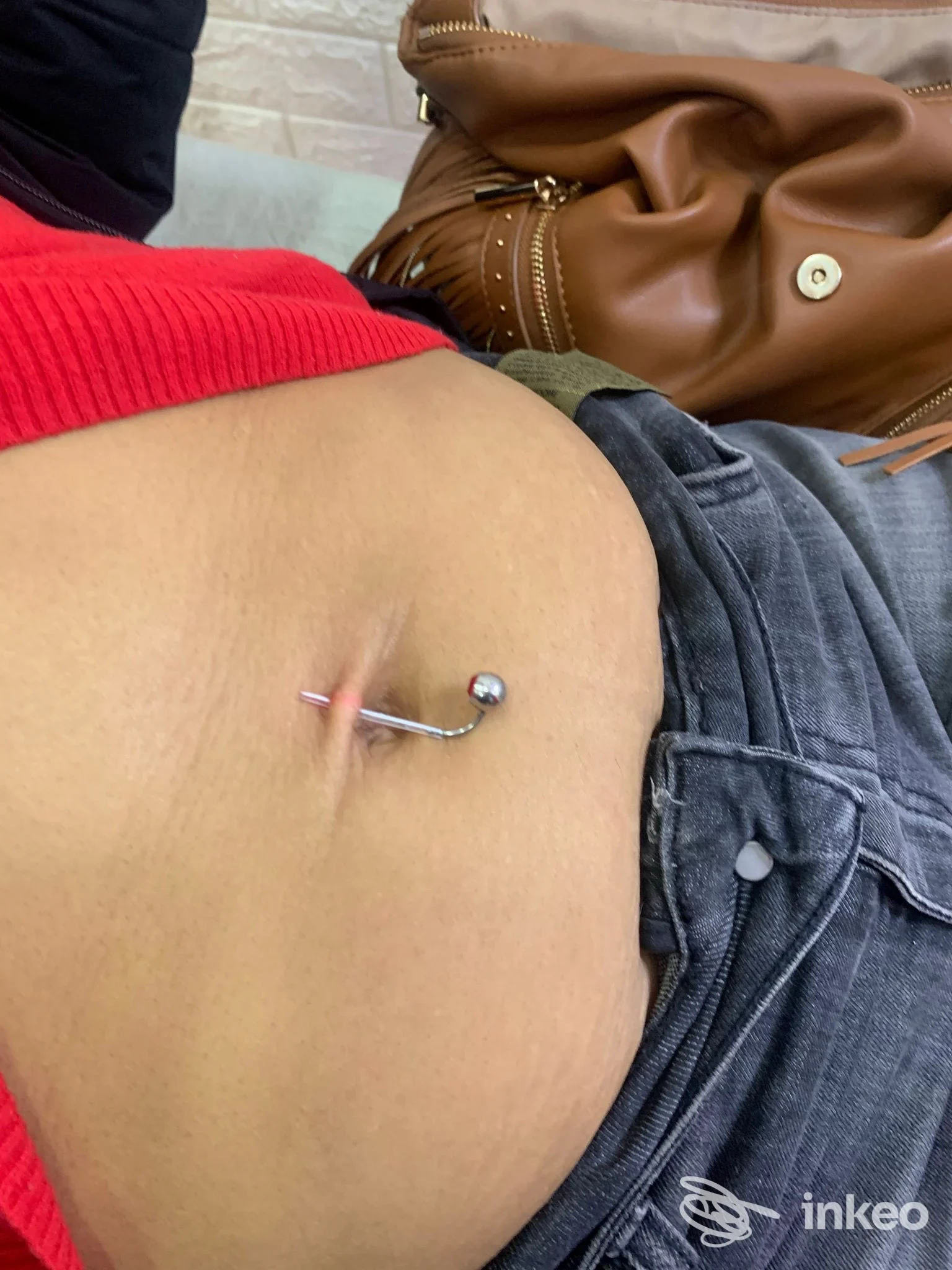 Piercing ombelicale con barra curva e pallina metallica su addome femminile, foto per MOSÉ BEAUTY SHOP, Napoli.