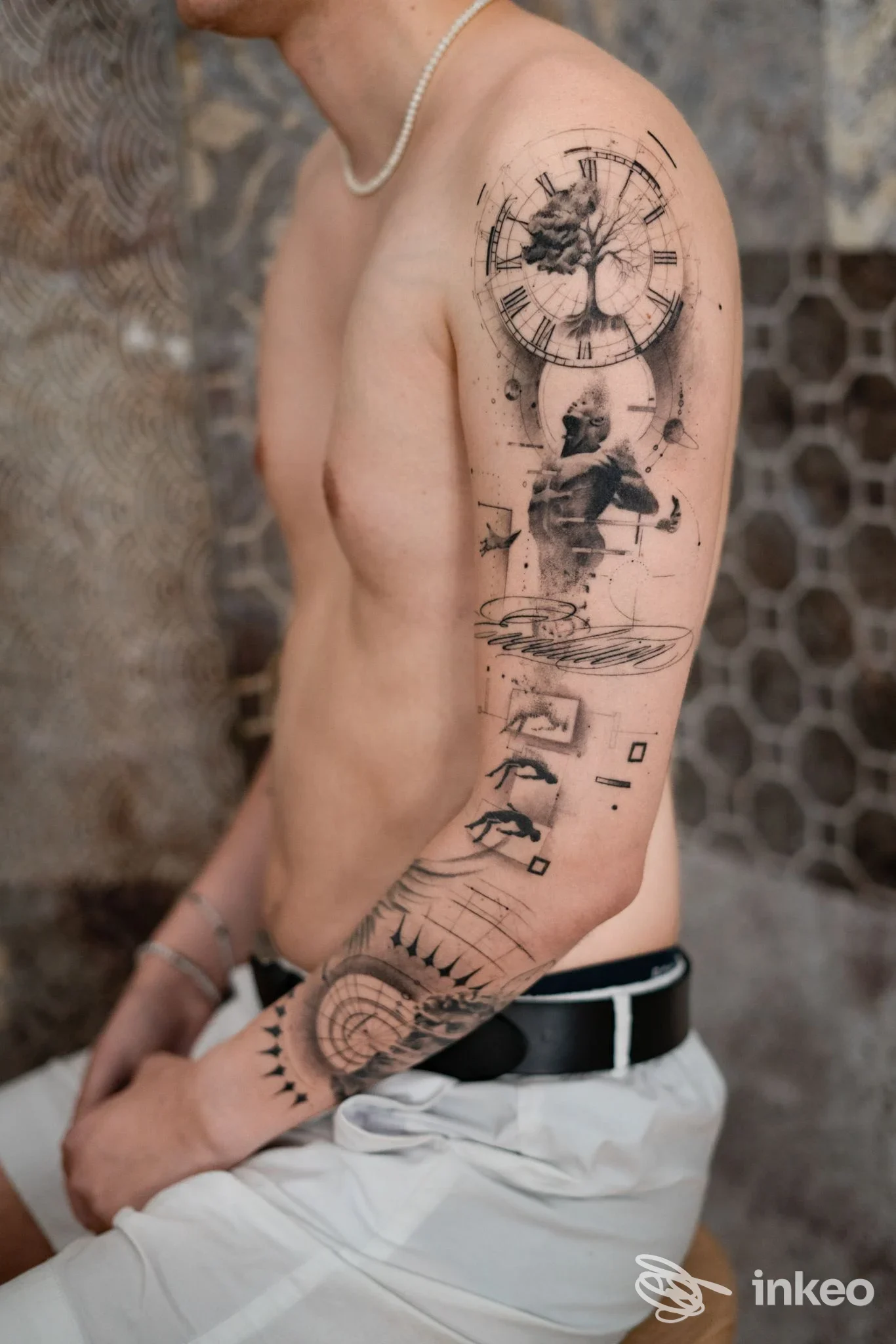 Tatuaggio a manica sul braccio con orologio e figure stilizzate, foto di Ultraviolet Studio Tattoo Pesaro, Pesaro.