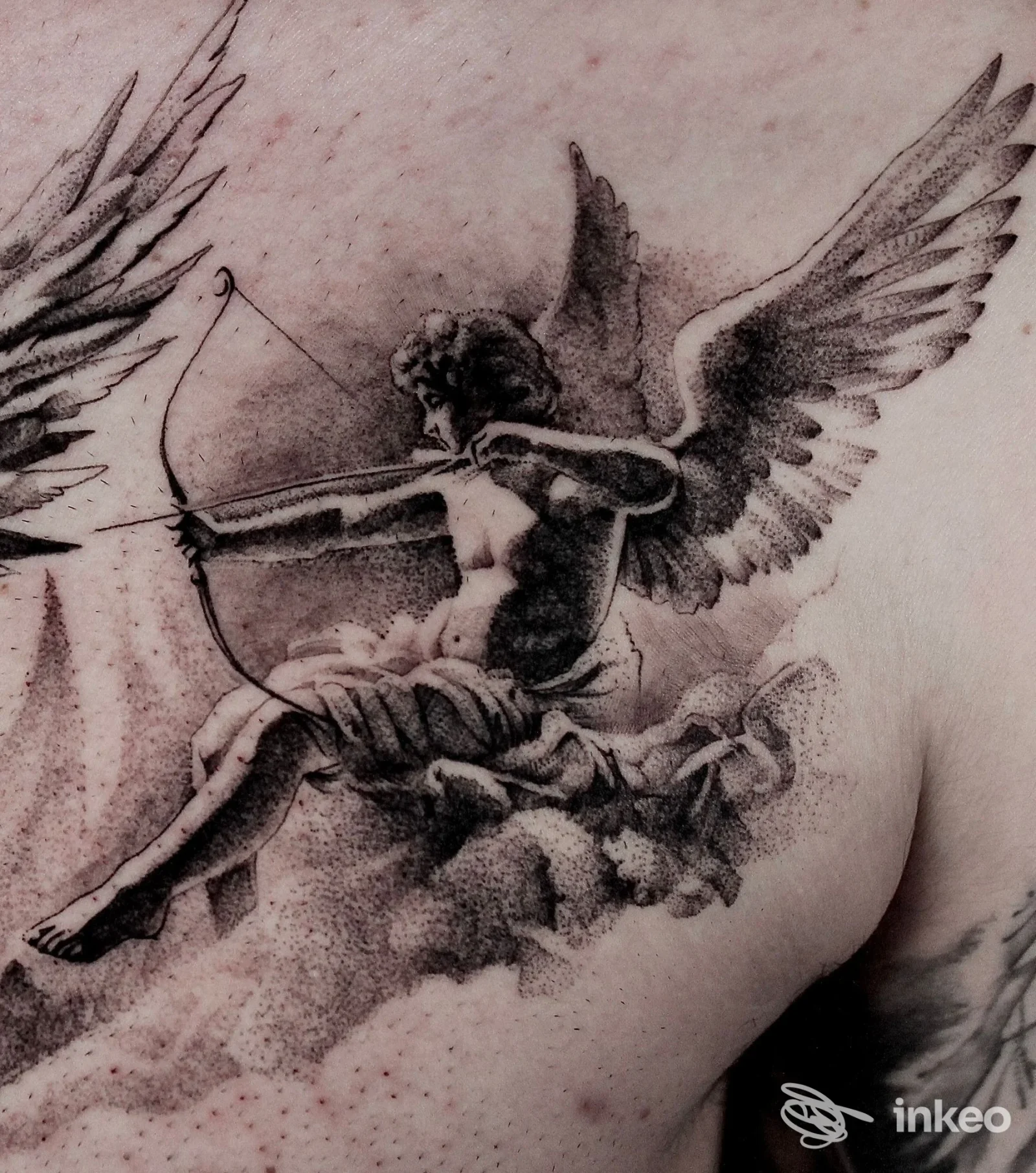 Tatuaggio in bianco e nero di un angelo con arco sul petto, foto fornita da Mauro Petri Tattoo Studio, Brindisi.
