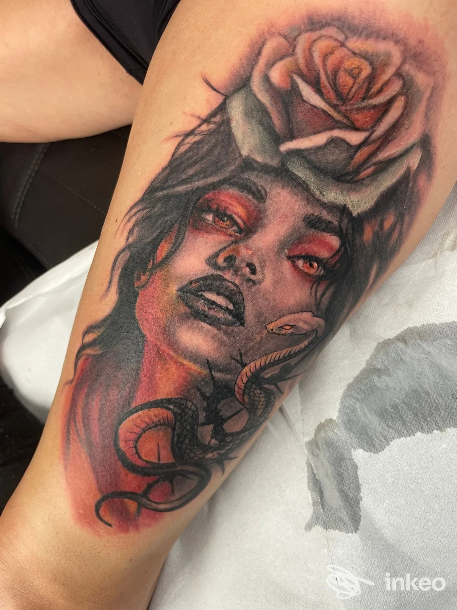 Dettaglio di tatuaggio su coscia: ritratto femminile colorato con rosa e serpente — The art of Leonardo Meschini, Civita Castellana.