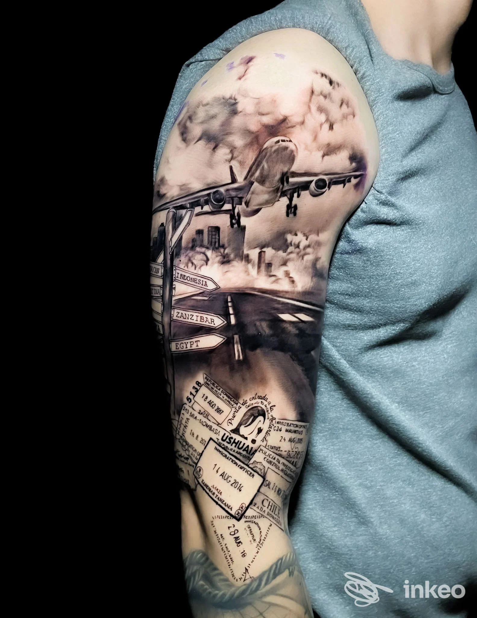 Tattoo a tema viaggio sull’avambraccio con aereo, biglietti e mappe: lavoro corporeo reale su pelle, foto singola, senza overlay.