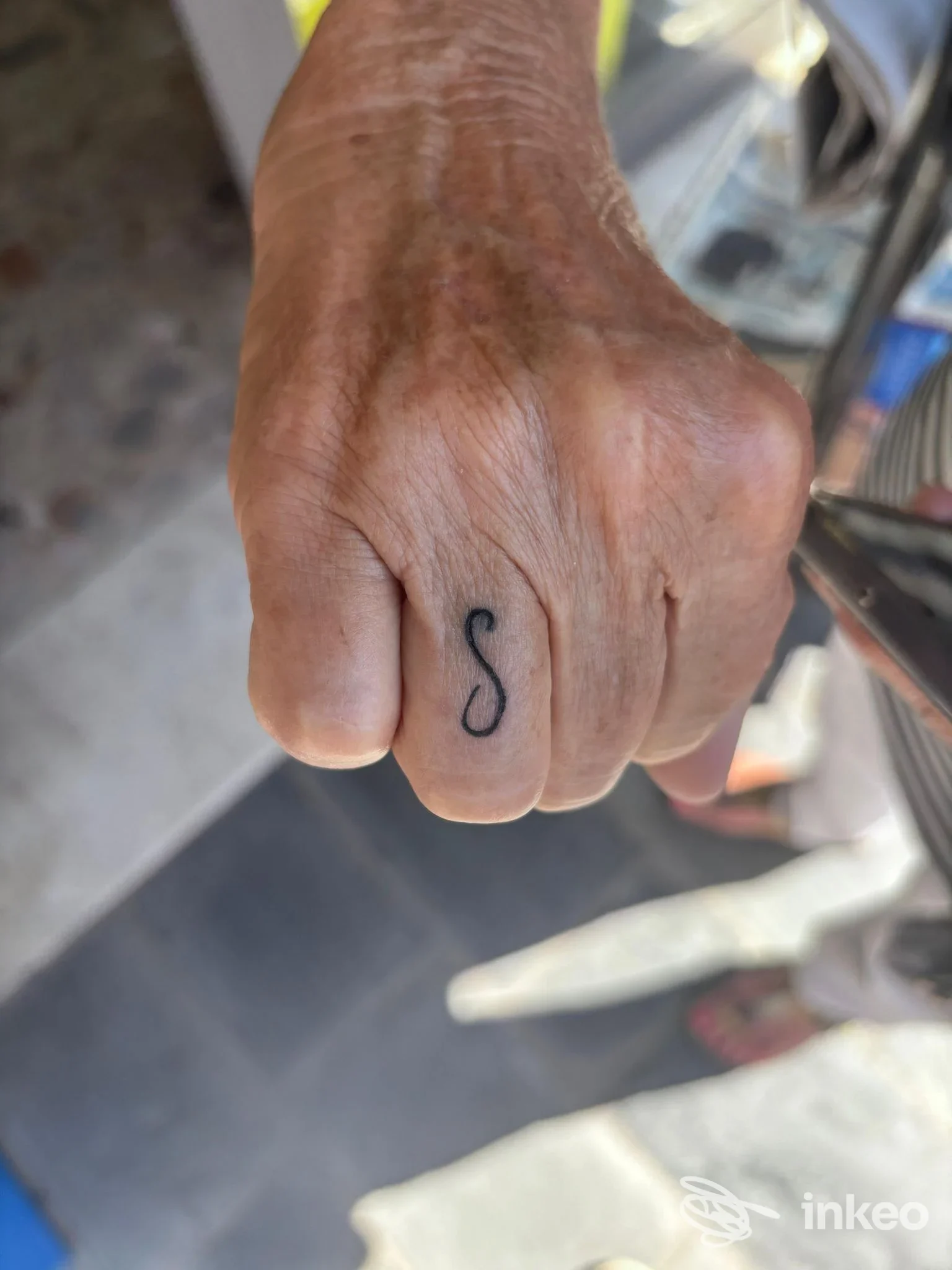 Primo piano di una mano con piccolo tatuaggio nero a forma di S sull'anulare, lavoro mostrato dallo studio La Bruma a San Lorenzo al Mare.