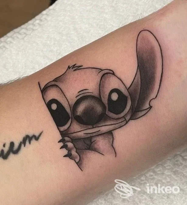 Tatuaggio in bianco e nero di Stitch sull'avambraccio interno, realizzato da Lost Love Tattoo Studio a Monterotondo.