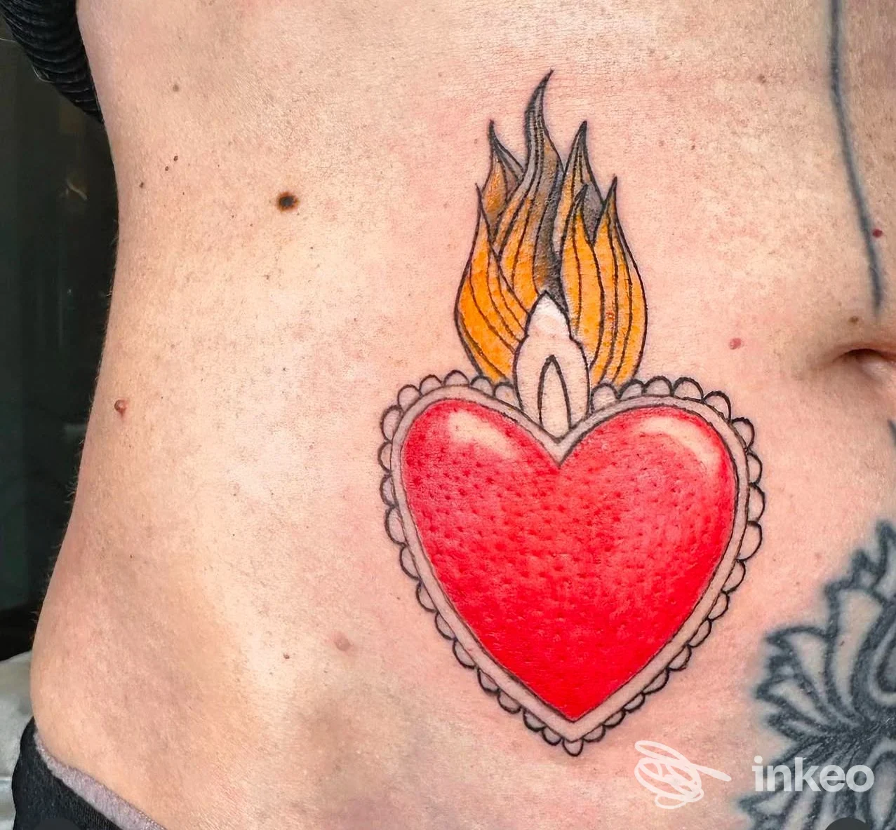 Cuore sacro con fiamme tatuato sul fianco, realizzato da Lucilla Panerai a Calenzano.