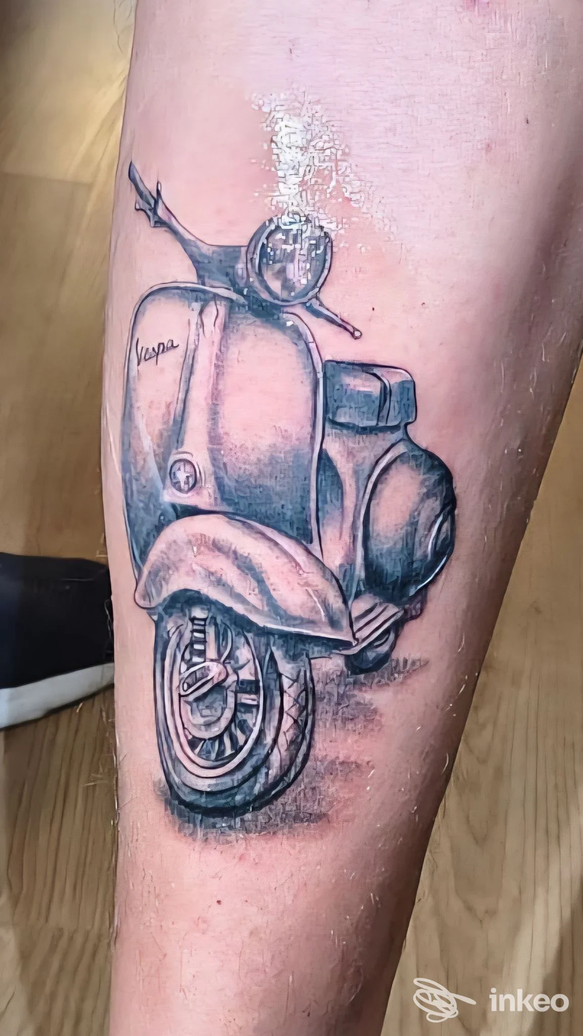 Tatuaggio in bianco e nero di una Vespa sul polpaccio, Noire Atelier, Bolzano.