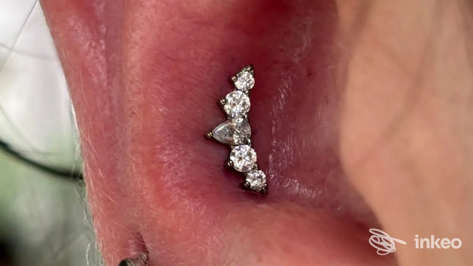 Primo piano di piercing all'orecchio con gioiello a cluster, eseguito da Cinnie Bodypiercer, Trieste.