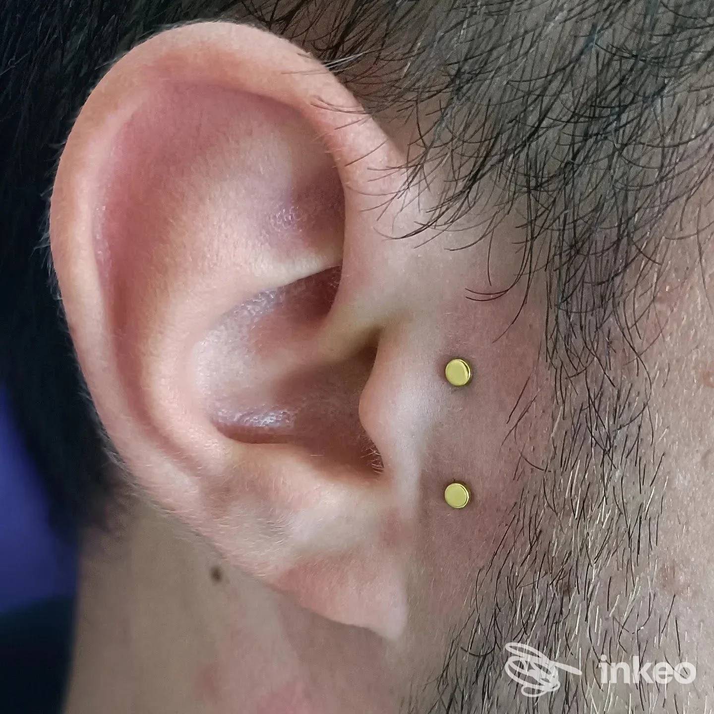 Primo piano di orecchio con due micro-piercing dorati, foto condivisa da Il Negozino di Di Gaetano Emanuela a Siena.