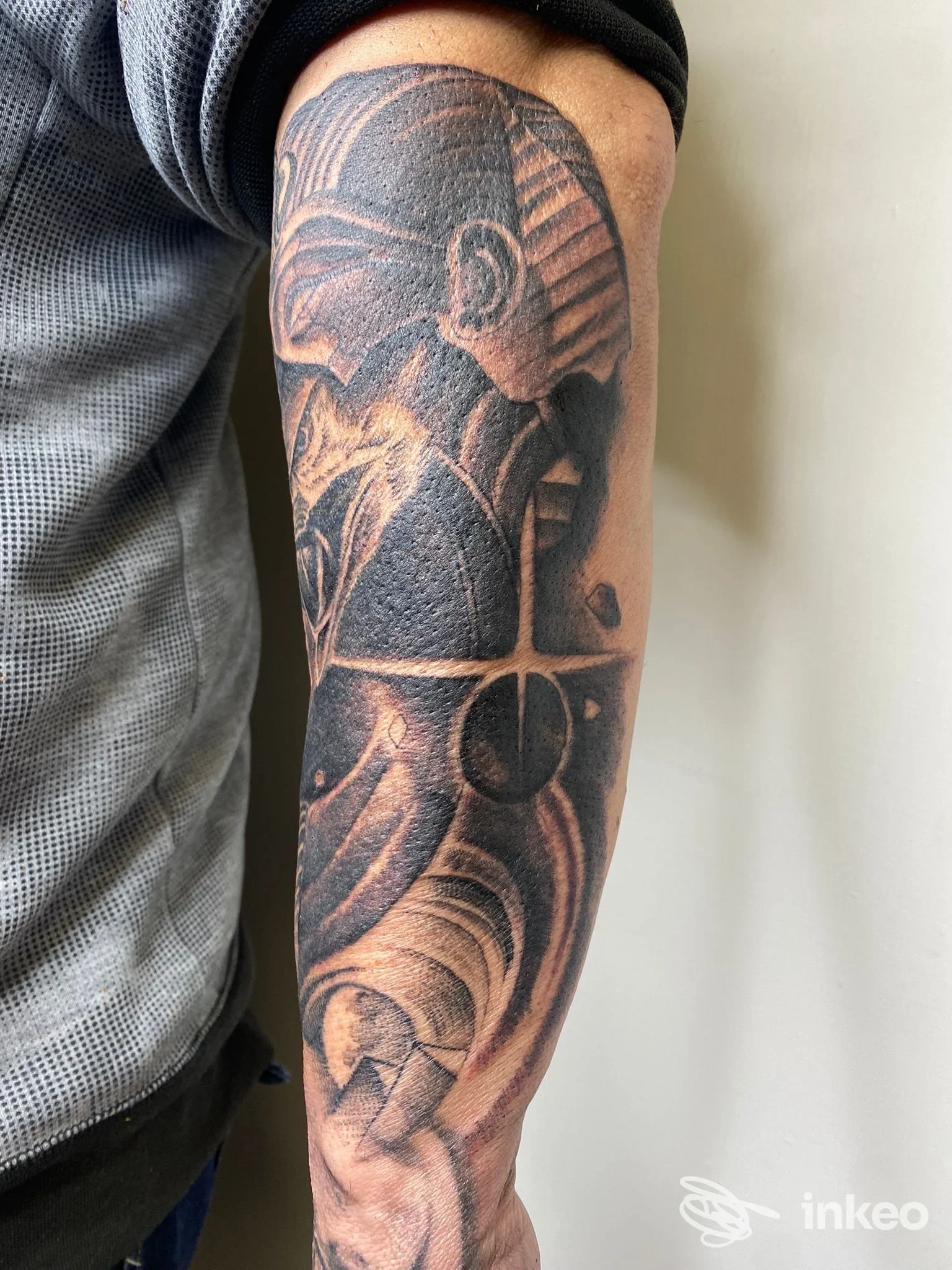 Tatuaggio su avambraccio che mostra figure stilizzate e ampie aree blackwork, foto inviata dallo studio Babau a Savona.