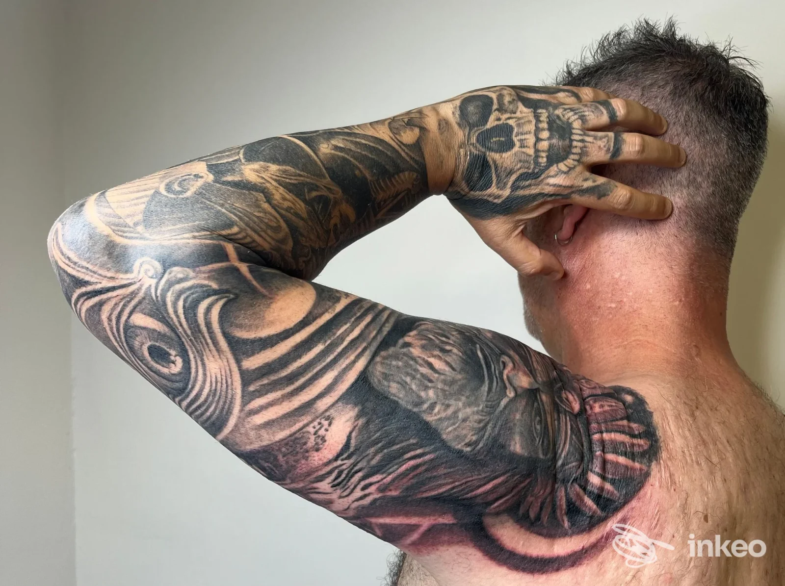Vista posteriore di braccio tatuato con manica nera su mano, spalla e petto; immagine fornita dallo studio Babau, Savona.