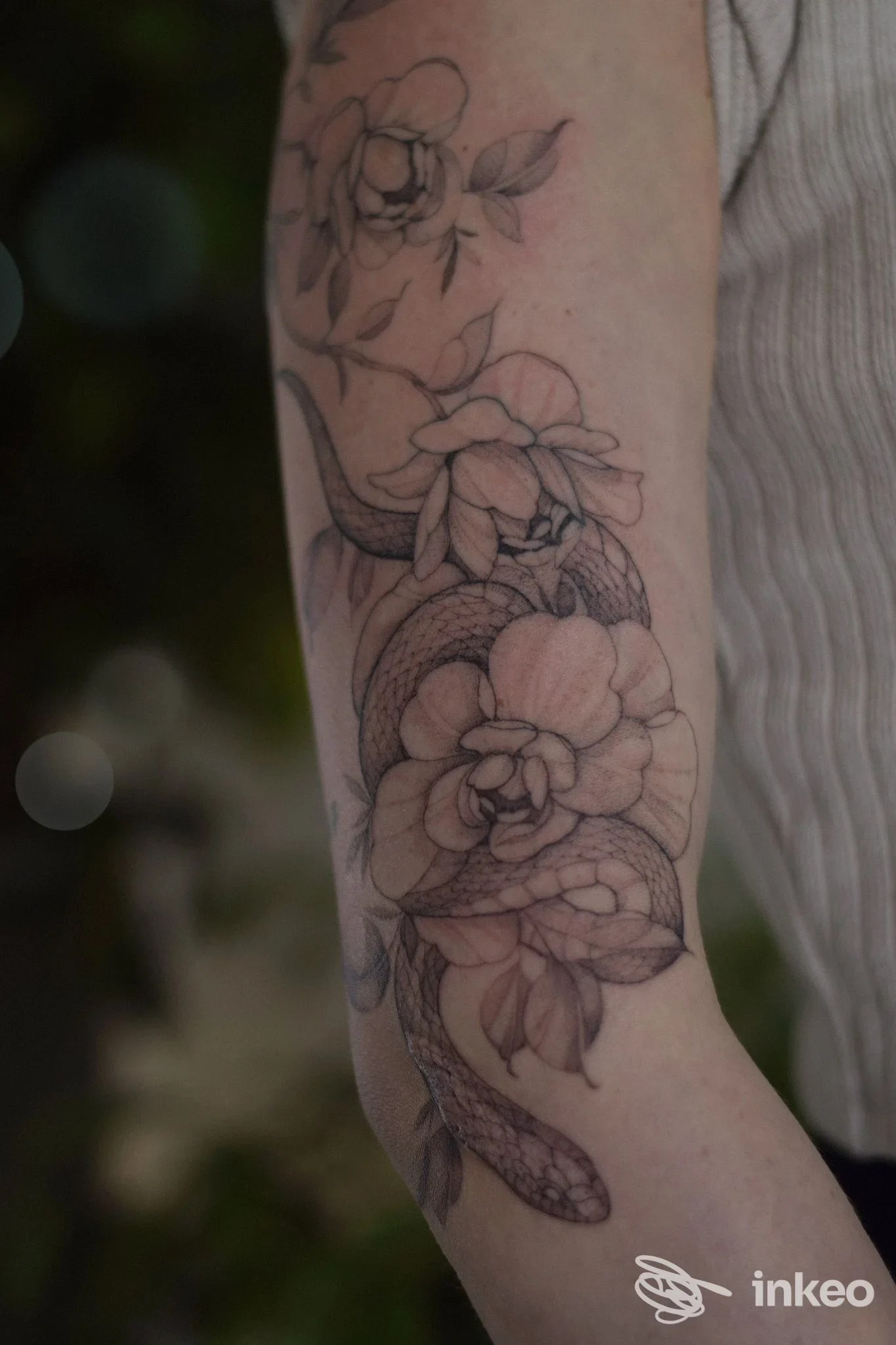 Tattoo floreale su avambraccio di una persona, tratteggio e shading visibili sulla pelle, senza volto nella cornice. Studio Atelier Selva, città non indicata.