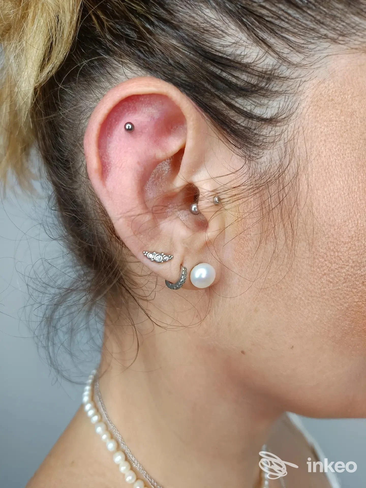 Primo piano dell'orecchio con più piercing realizzati da Aurora Veleno Beauty Artist a Foggia, dettagli dei gioielli e del lobo perlaceo.