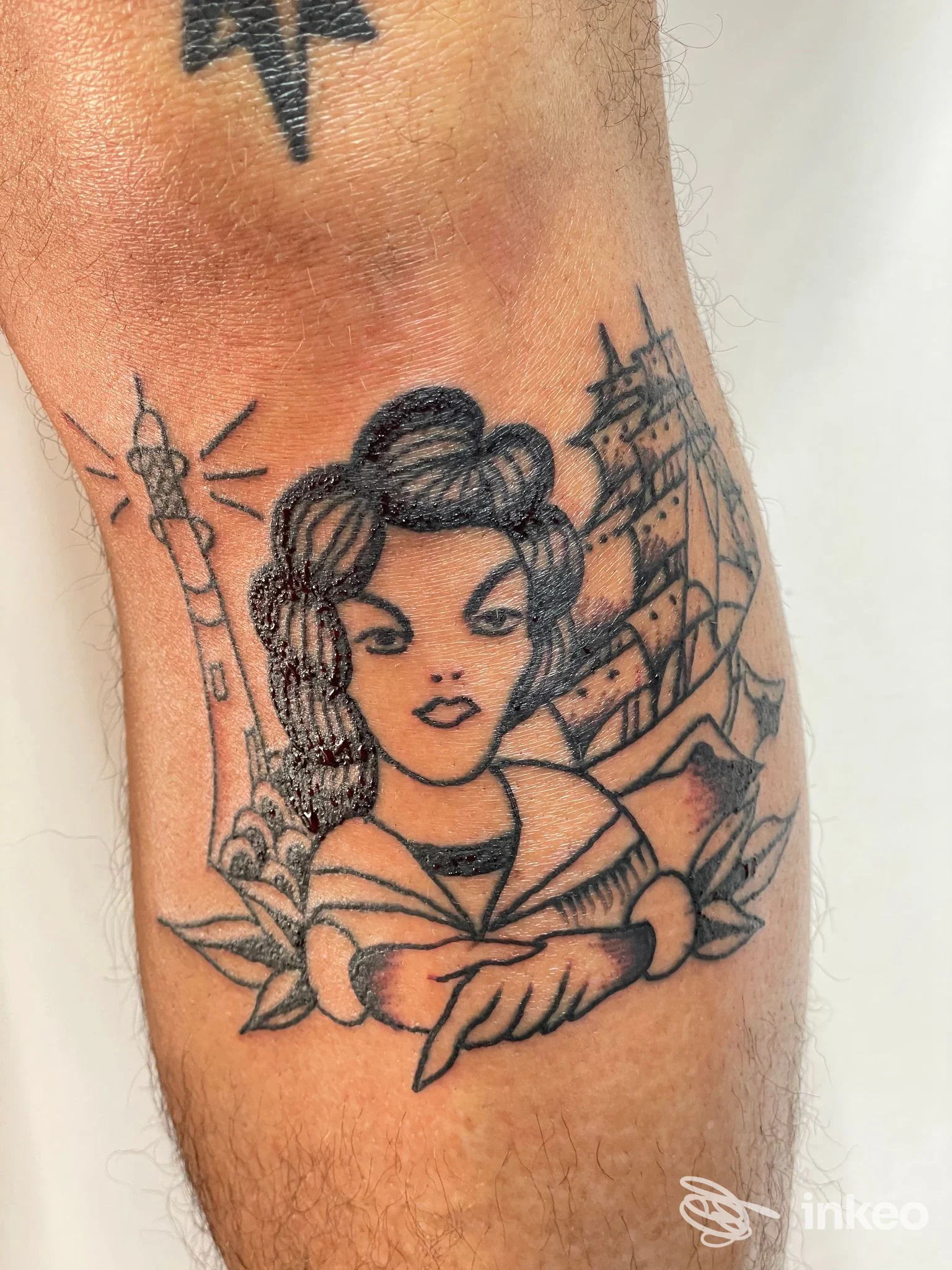 Tatuaggio tradizionale in nero su avambraccio con ritratto femminile, nave a vele e faro. Shangri-La, Genova.