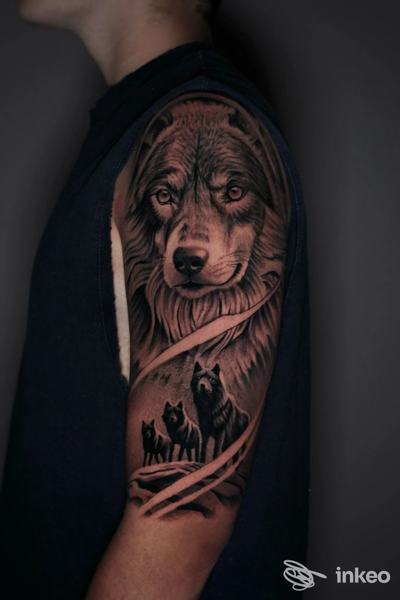 Tattoo realistico di un lupo sul braccio con cuccioli, visibile sulla pelle di una persona; nessun volto intero visibile.