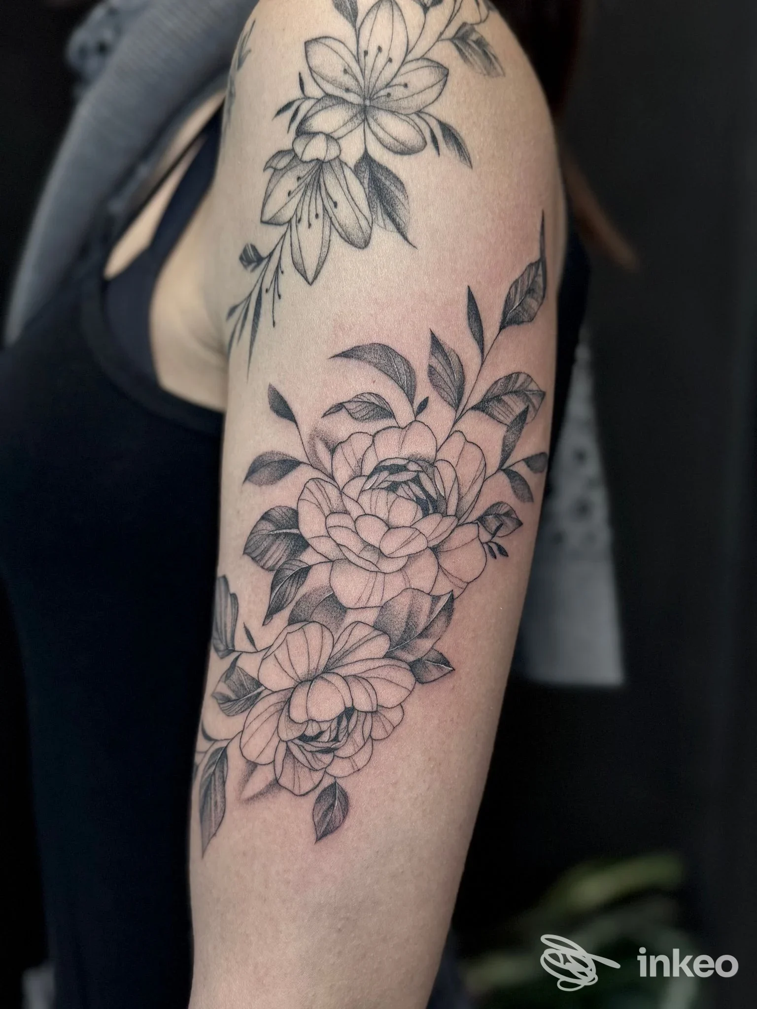 Tatuaggio floreale in bianco e nero sul braccio superiore, realizzato da Noeink a Pontecorvo.