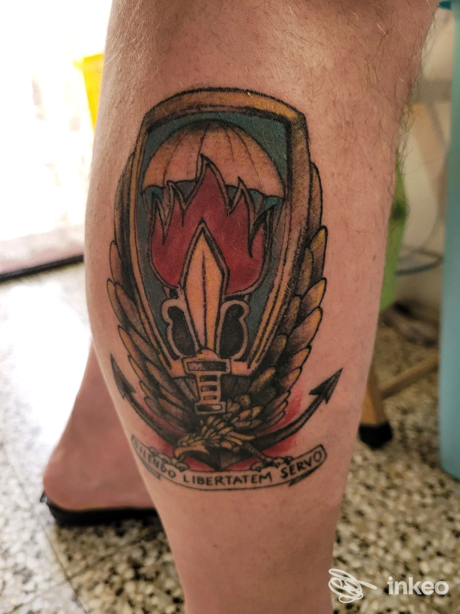 Tatuaggio colorato su polpaccio realizzato da Nabbamb' a Barletta, elmo stilizzato con fiamma e ali.